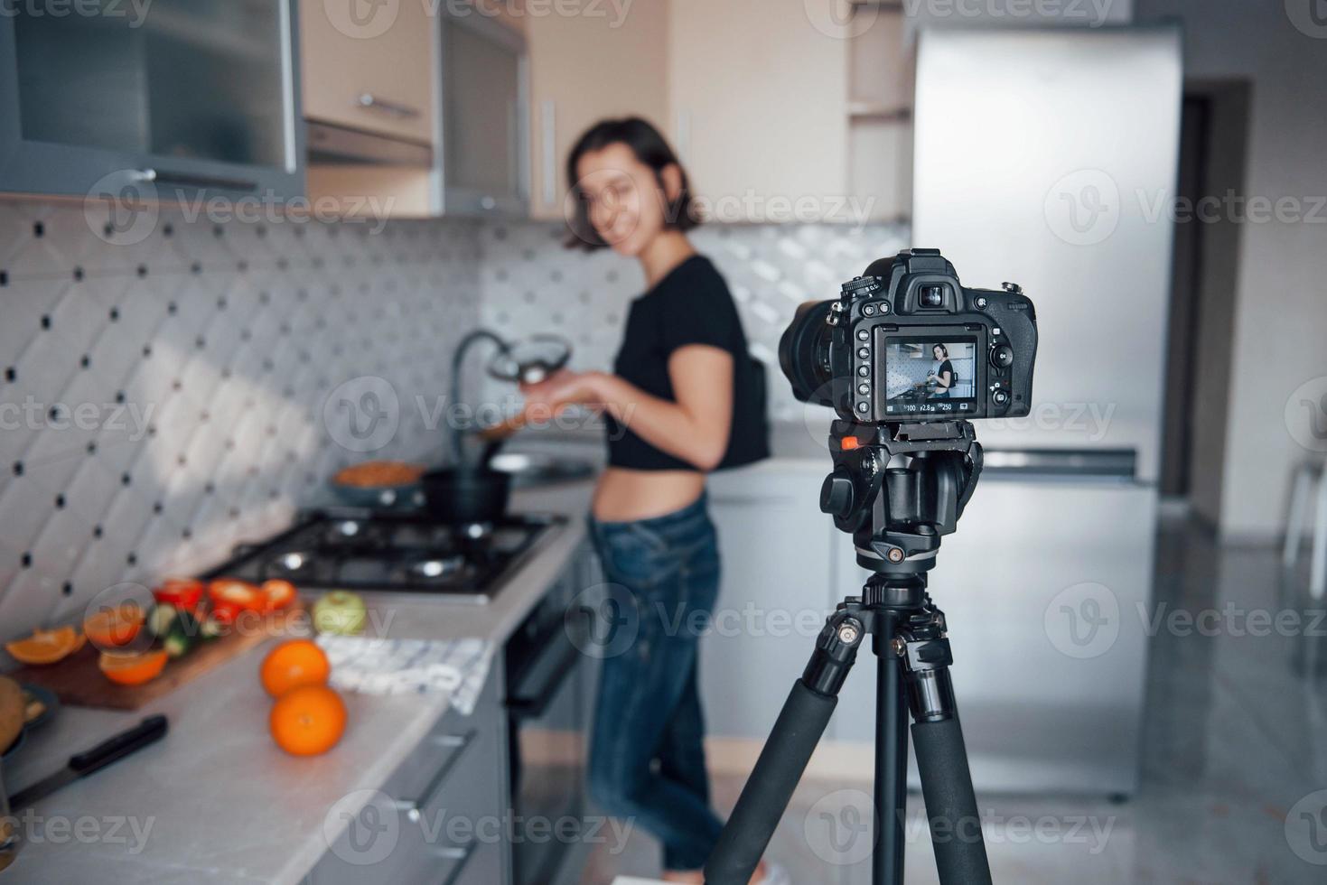 centrarse en la cámara. chica en la cocina moderna en casa a la hora del fin de semana por la mañana foto