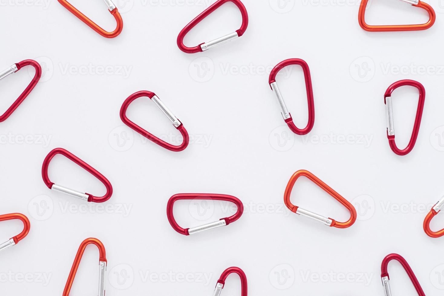 Trust and safety conception. Many of the red colored carabiners on lying on the white table photo