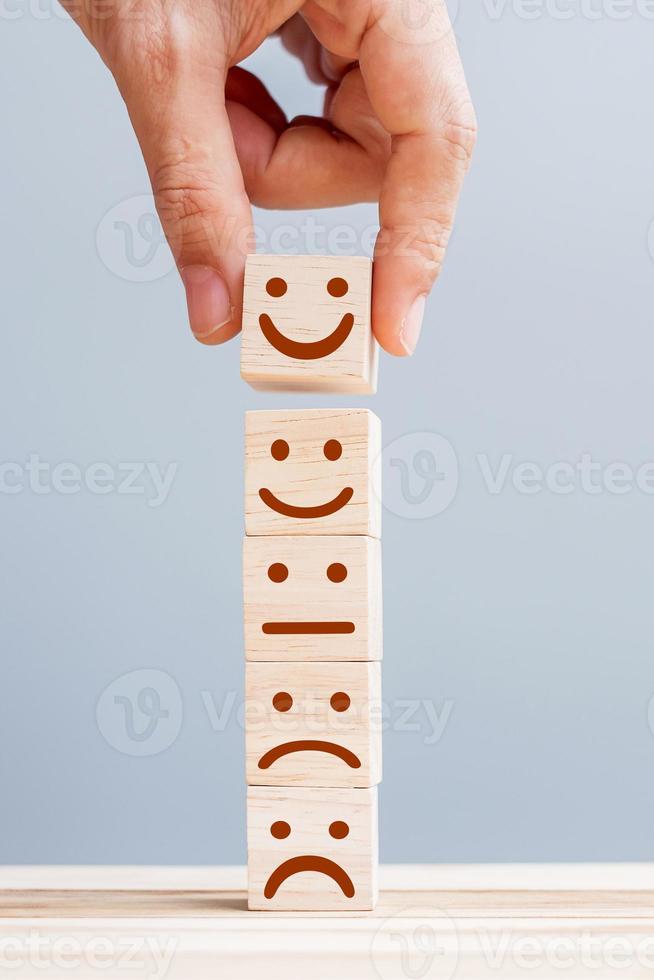 Hand holding smile face symbol on wooden cube blocks. Emotion, Service rating, ranking, customer review, satisfaction and feedback concept photo