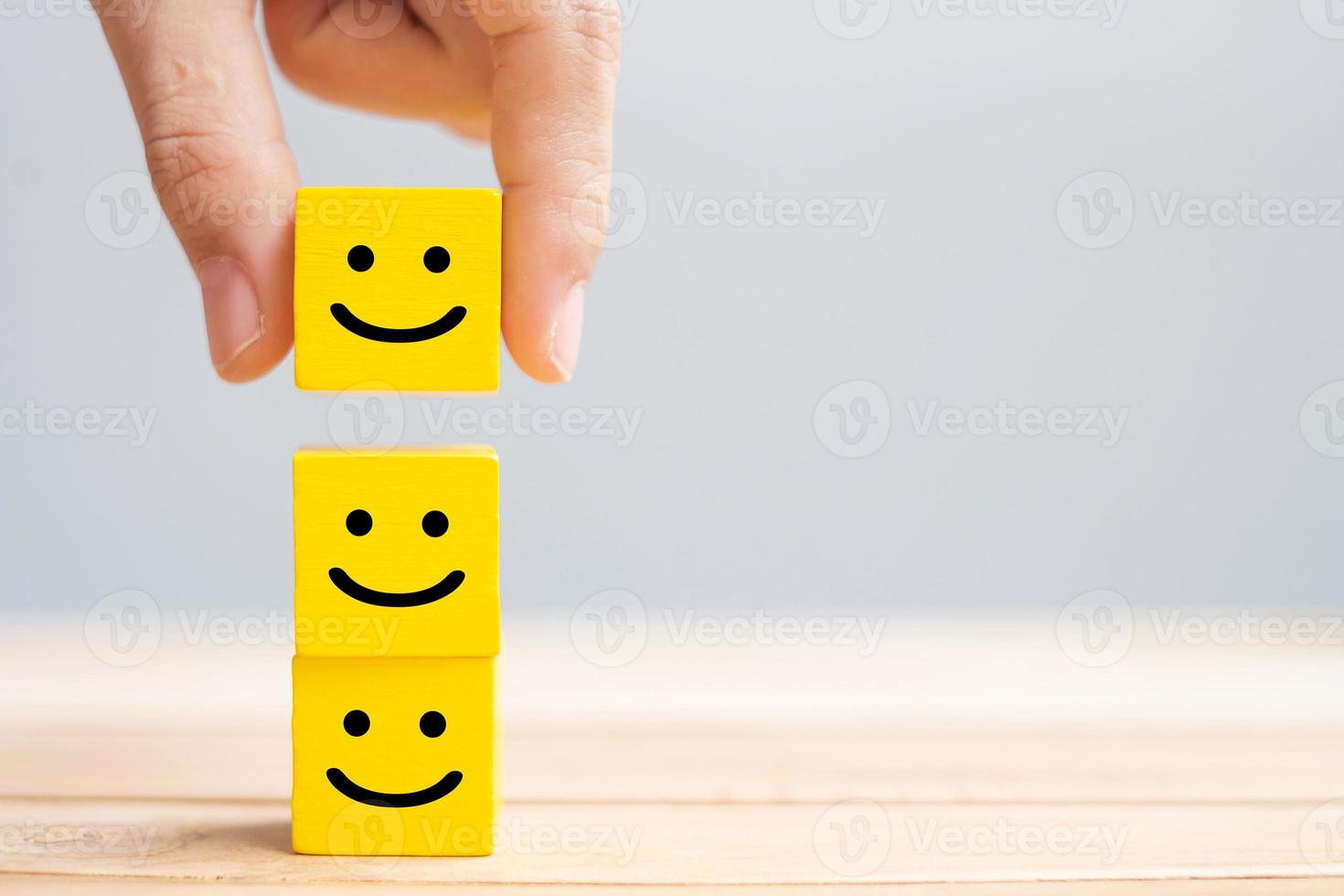 Hand holding smile face symbol on yellow wooden cube blocks. Emotion, Service rating, ranking, customer review, satisfaction and feedback concept photo