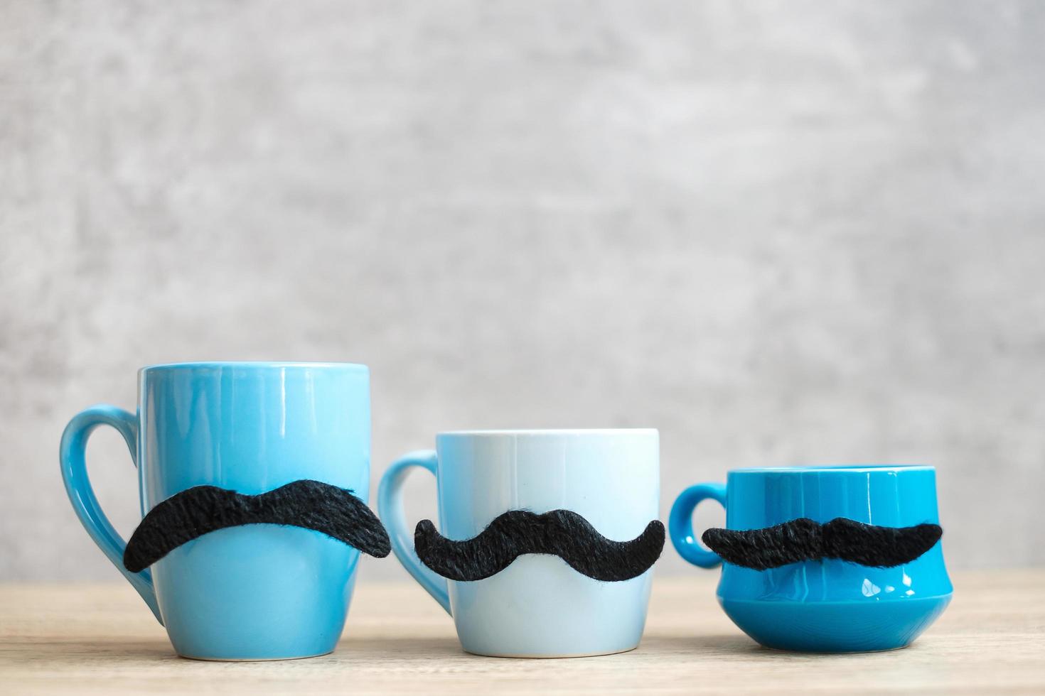 Blue coffee cup and tea mug with Black mustache decor on wood table background in the morning. Blue November, Happy Father day and International men day concept photo