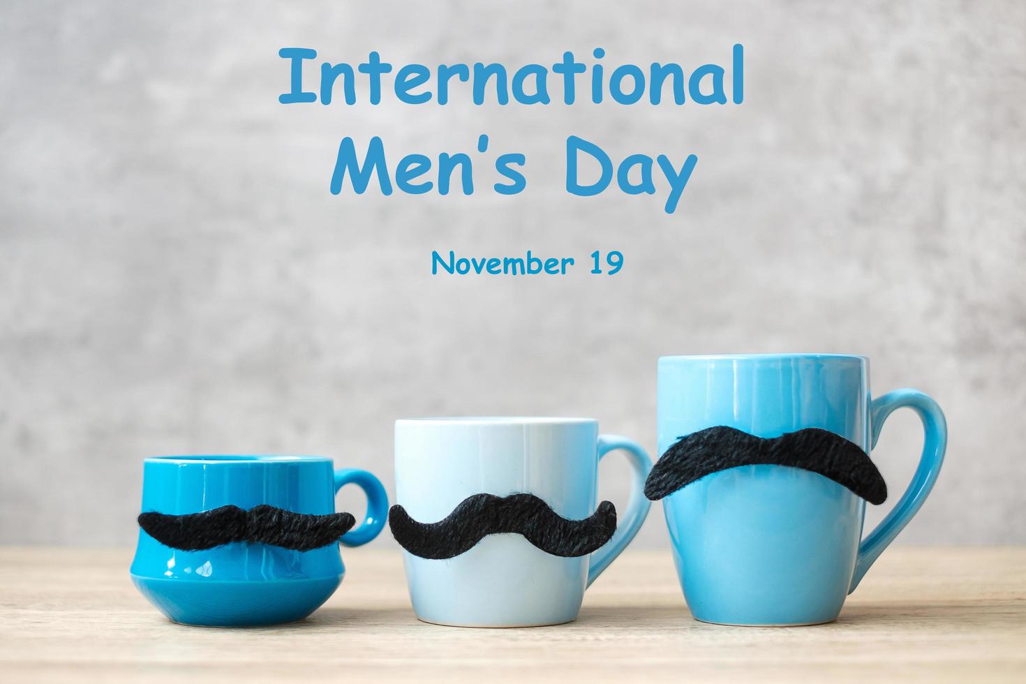 día internacional del hombre con taza de café azul o taza de té y decoración de bigote negro en la mesa. feliz día del padre y concepto de celebración foto