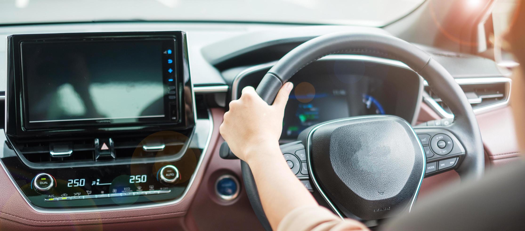 mujer conductora conduciendo un automóvil en la carretera, controlando a mano el volante en un automóvil eléctrico moderno. conceptos de transporte de viaje, viaje y seguridad foto