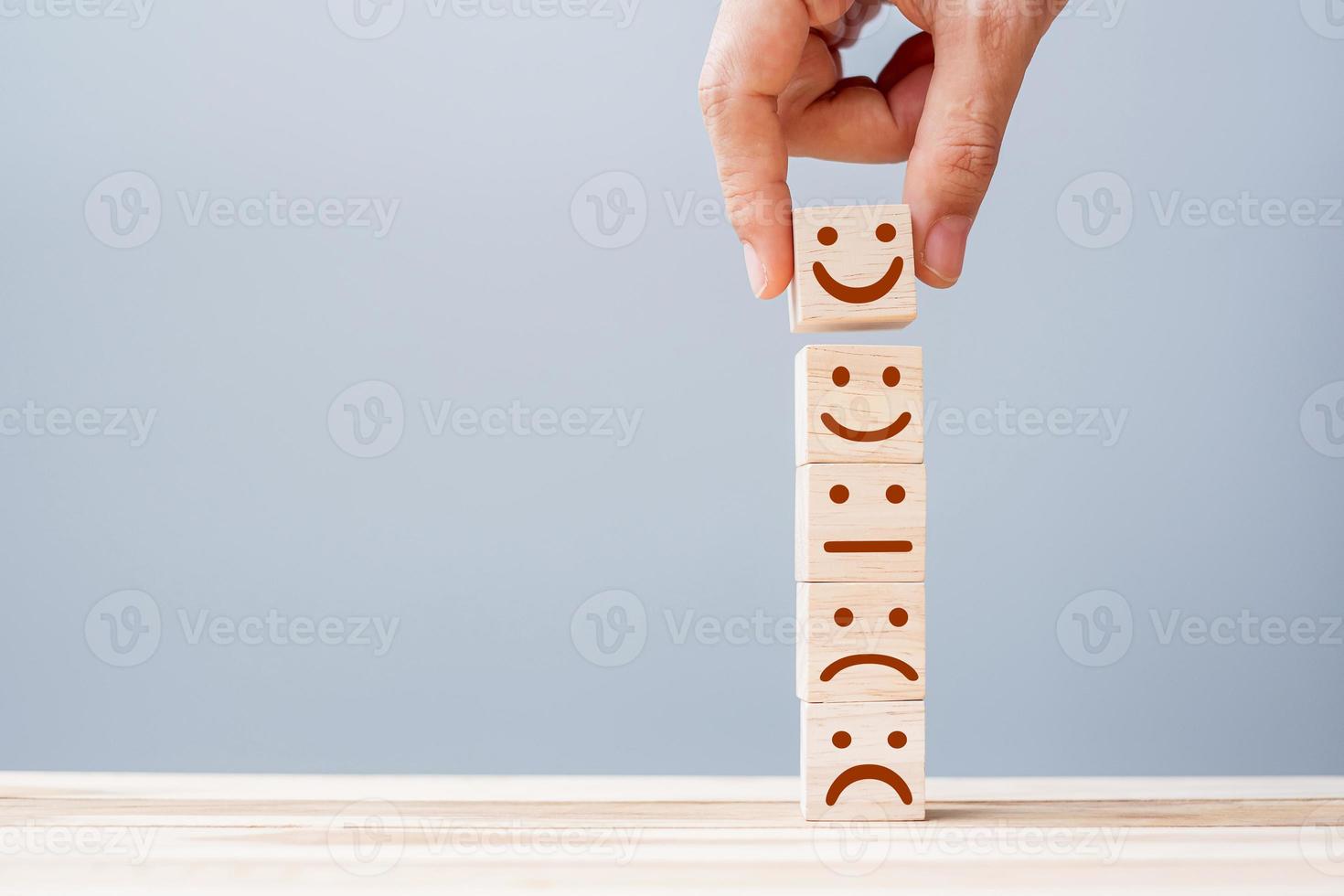 Hand holding smile face symbol on wooden cube blocks. Emotion, Service rating, ranking, customer review, satisfaction and feedback concept photo