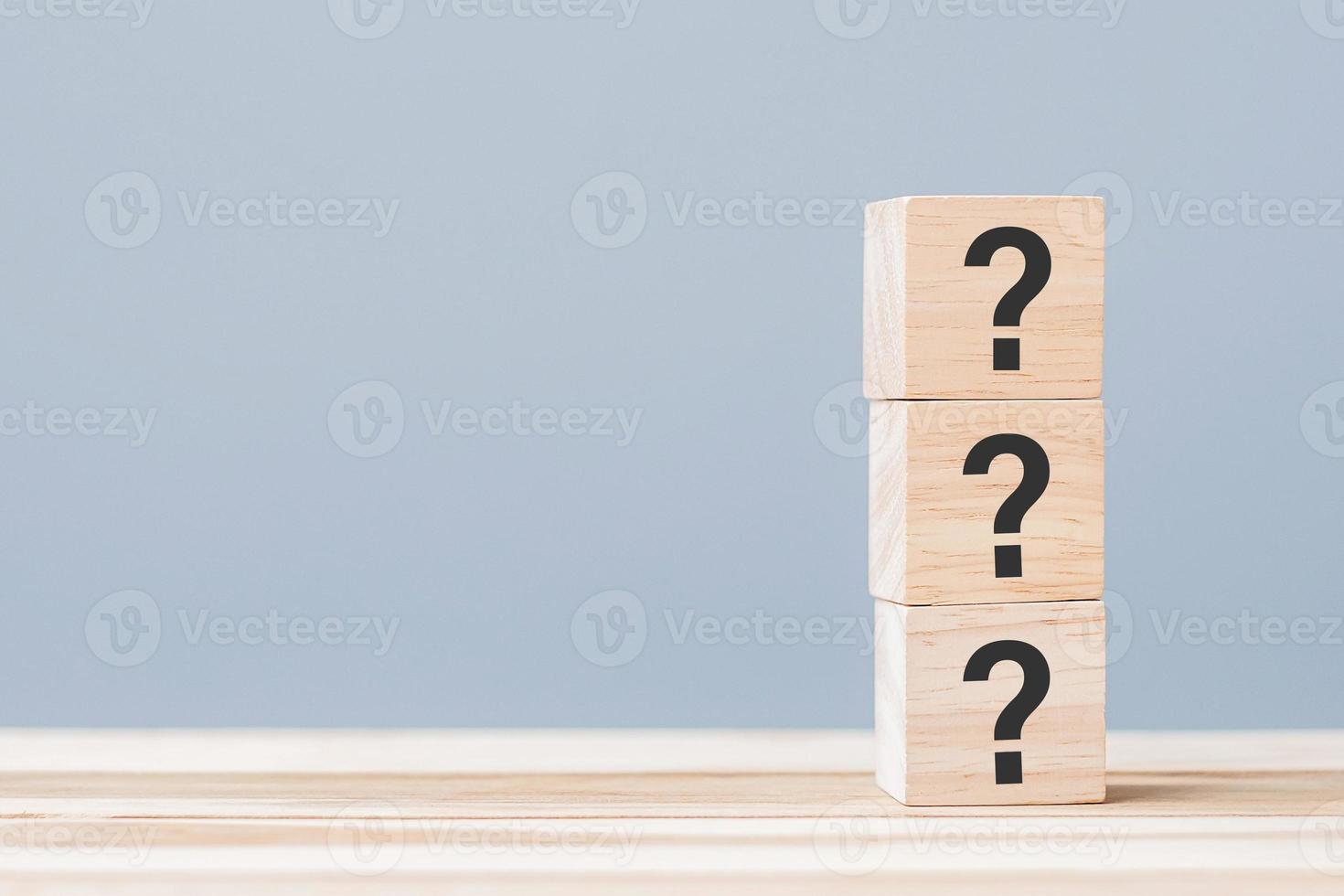 signo de interrogación en bloque de cubo de madera en el fondo de la mesa. faq, respuesta, q y a, conceptos de información, comunicación e interrogatorio foto