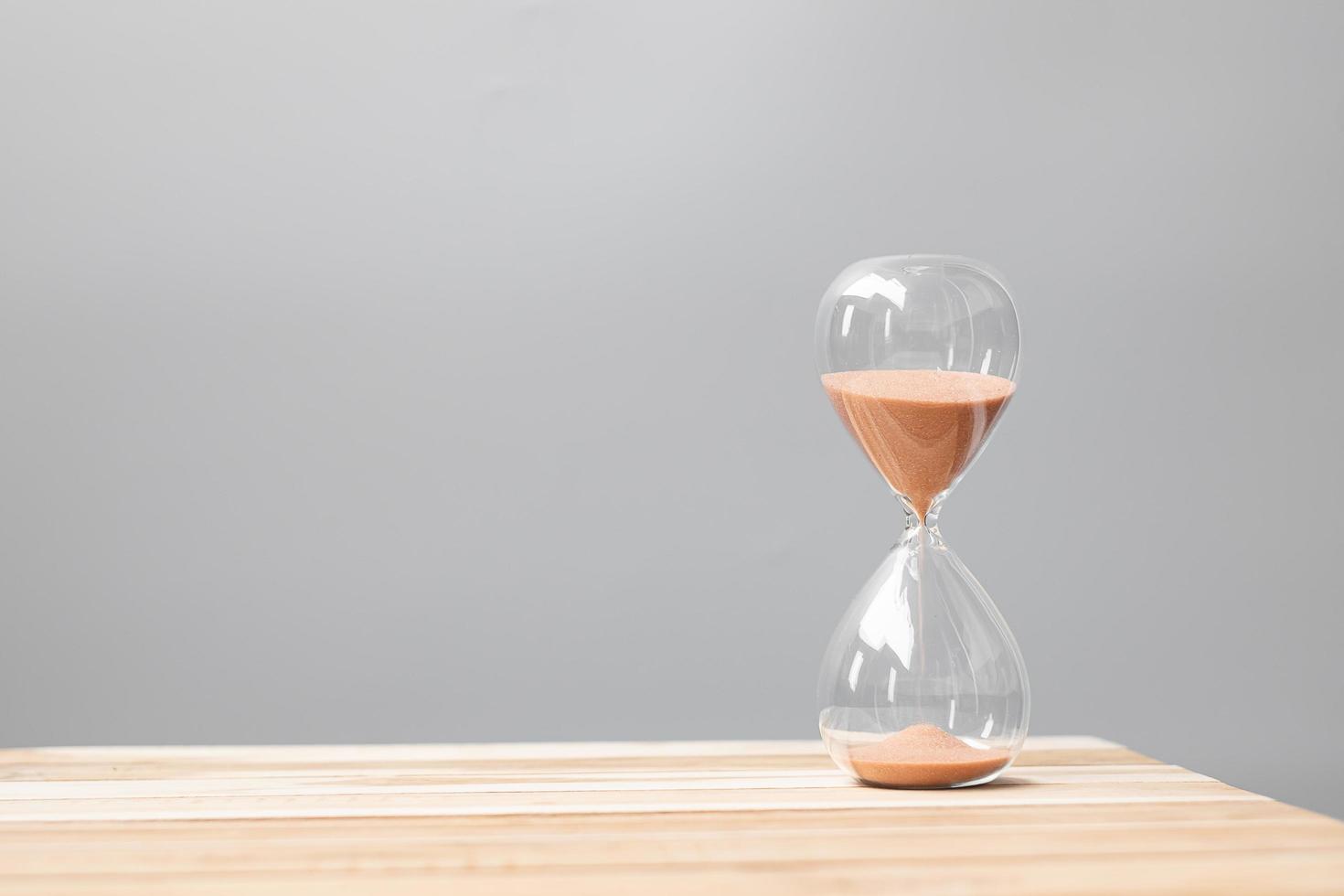 Hourglass on table office with copy space, Sand flowing through the bulb of Sandglass measuring the passing time. countdown, deadline, Life time and Retirement concept photo