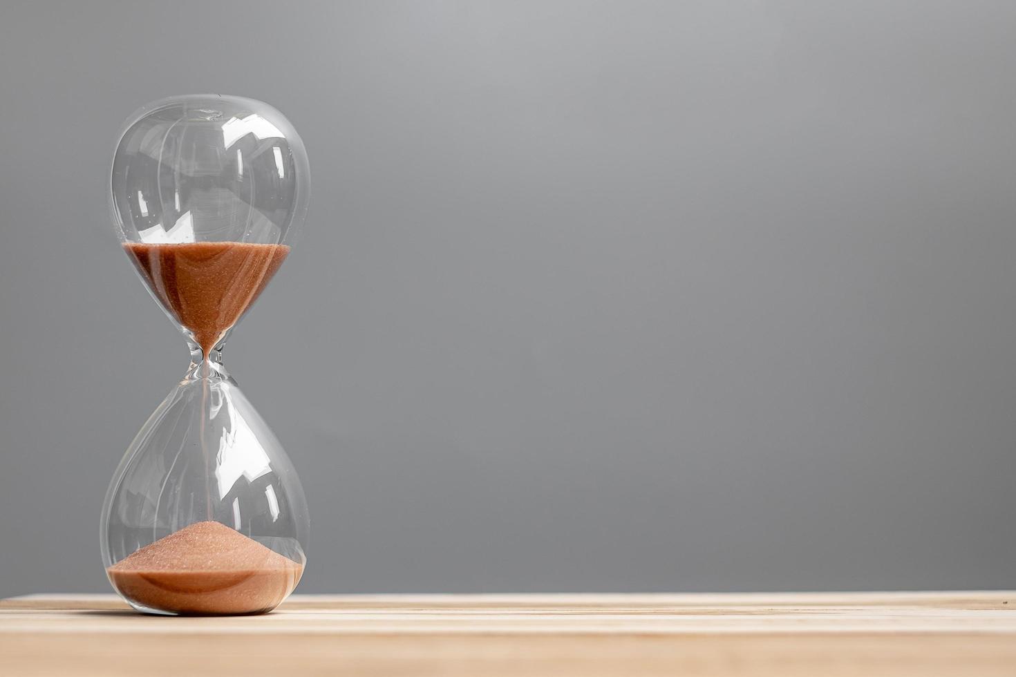 Hourglass on table office with copy space, Sand flowing through the bulb of Sandglass measuring the passing time. countdown, deadline, Life time and Retirement concept photo