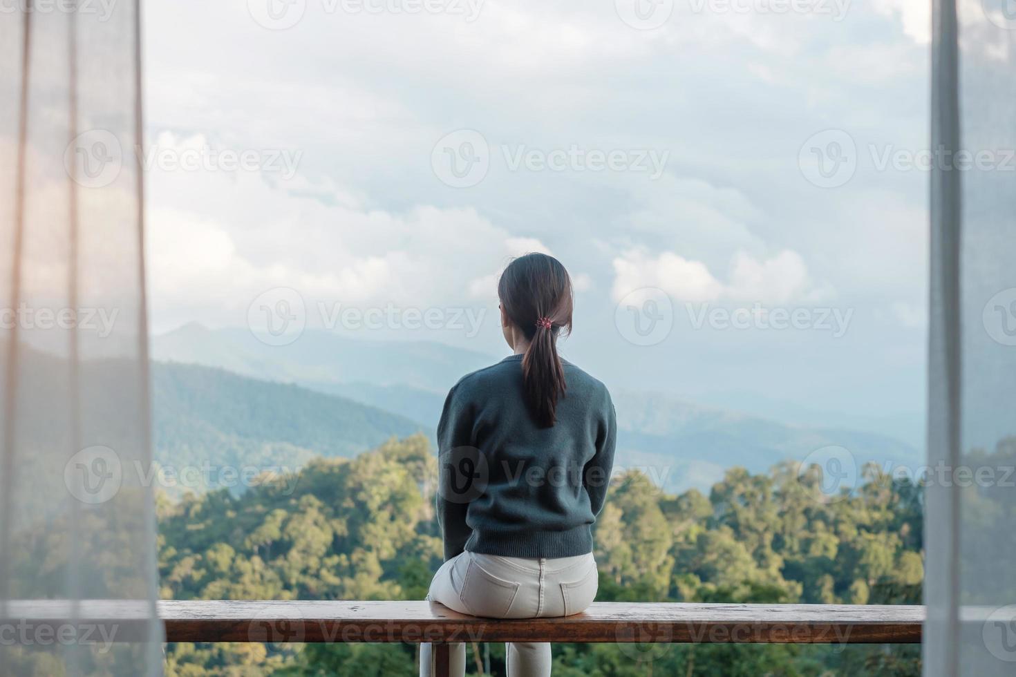 Happy woman relaxing and looking mountain view at countryside home or homestay in the morning. Vacation, blogger, SoloTravel, journey, trip and relaxing concept photo