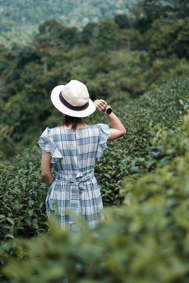 Happy woman tourist in blue dress and hat enjoy beautiful Tea garden.Traveler visiting in green natural hills in morning. travel, vacation, trip and journey concept photo