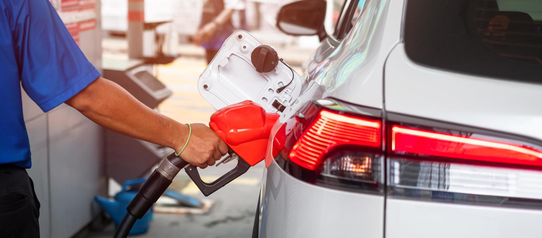 Man hand refuel to car, gasoline fuel nozzle in vehicle at petrol station. Oil Price, petroleum economy, inflation and commodity concept photo