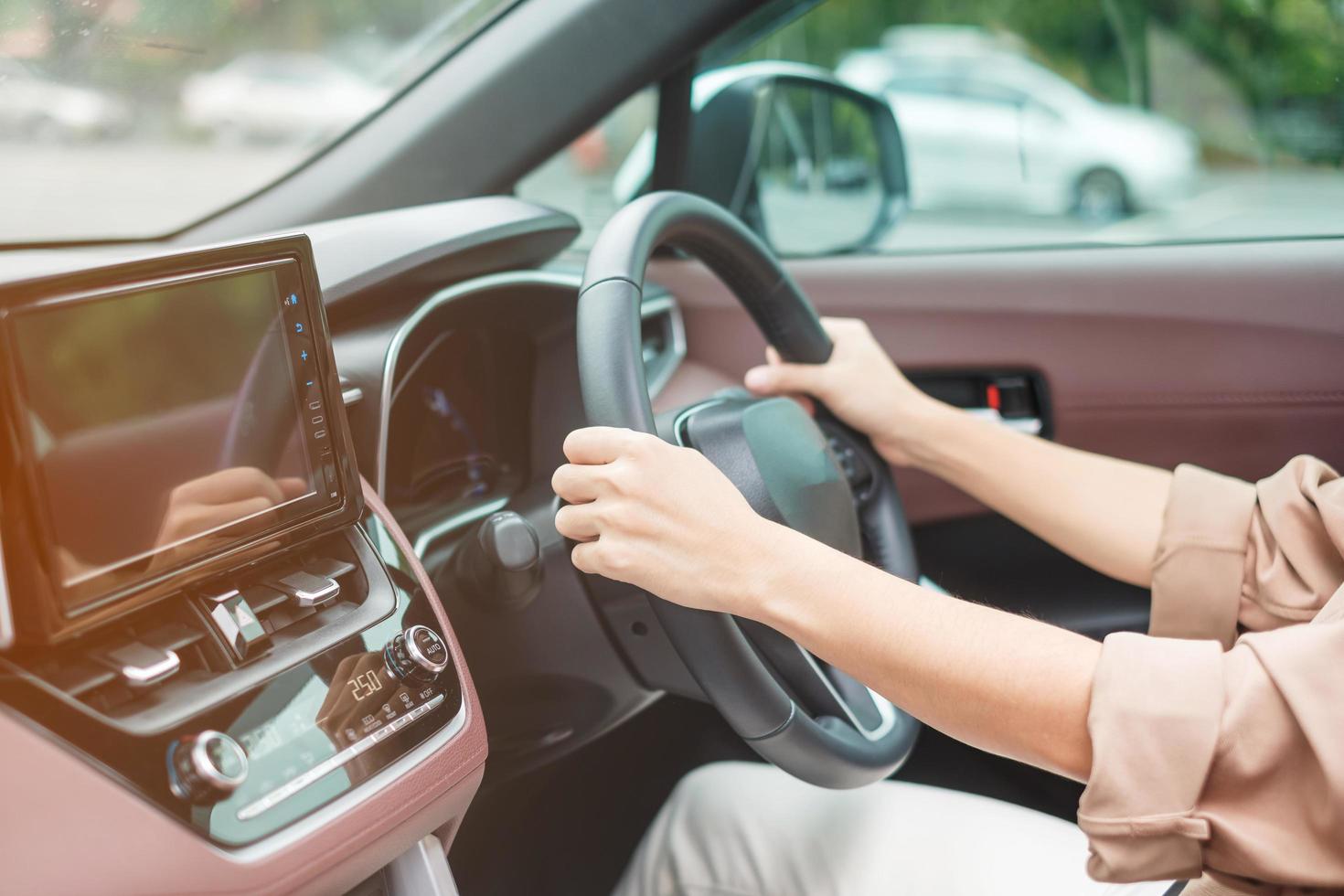 woman driver driving a car on the road, hand controlling steering wheel in electric modern automobile. Journey, trip and safety Transportation concepts photo