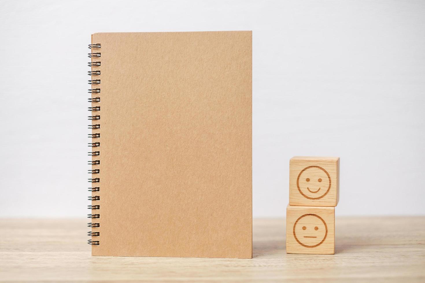 emotion face block and notebook on table. Emoticon for customer review, satisfaction, mood, mental health and feedback concept photo