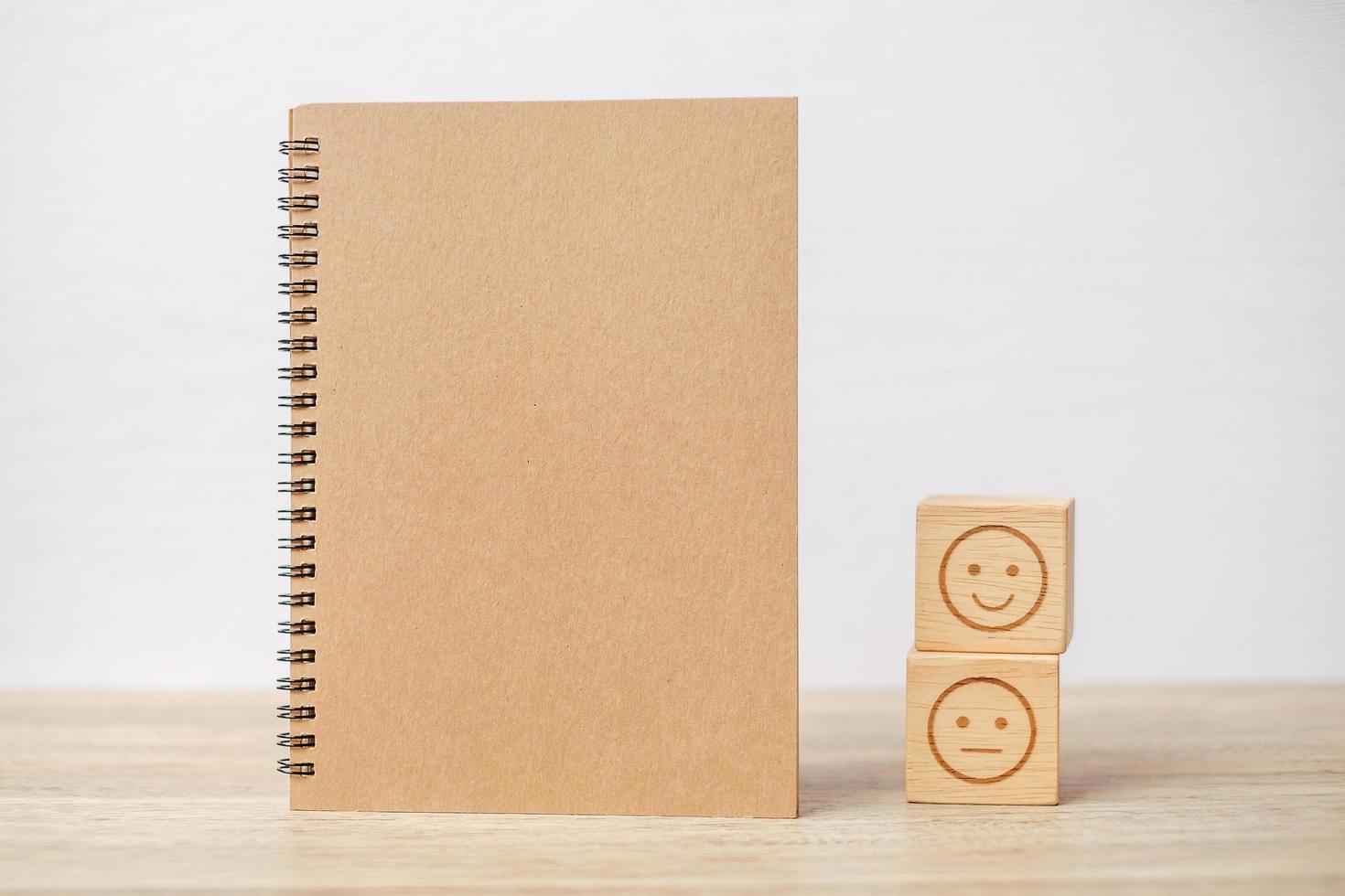 bloque de cara de emoción y cuaderno en la mesa. emoticono para la revisión del cliente, la satisfacción, el estado de ánimo, la salud mental y el concepto de retroalimentación foto