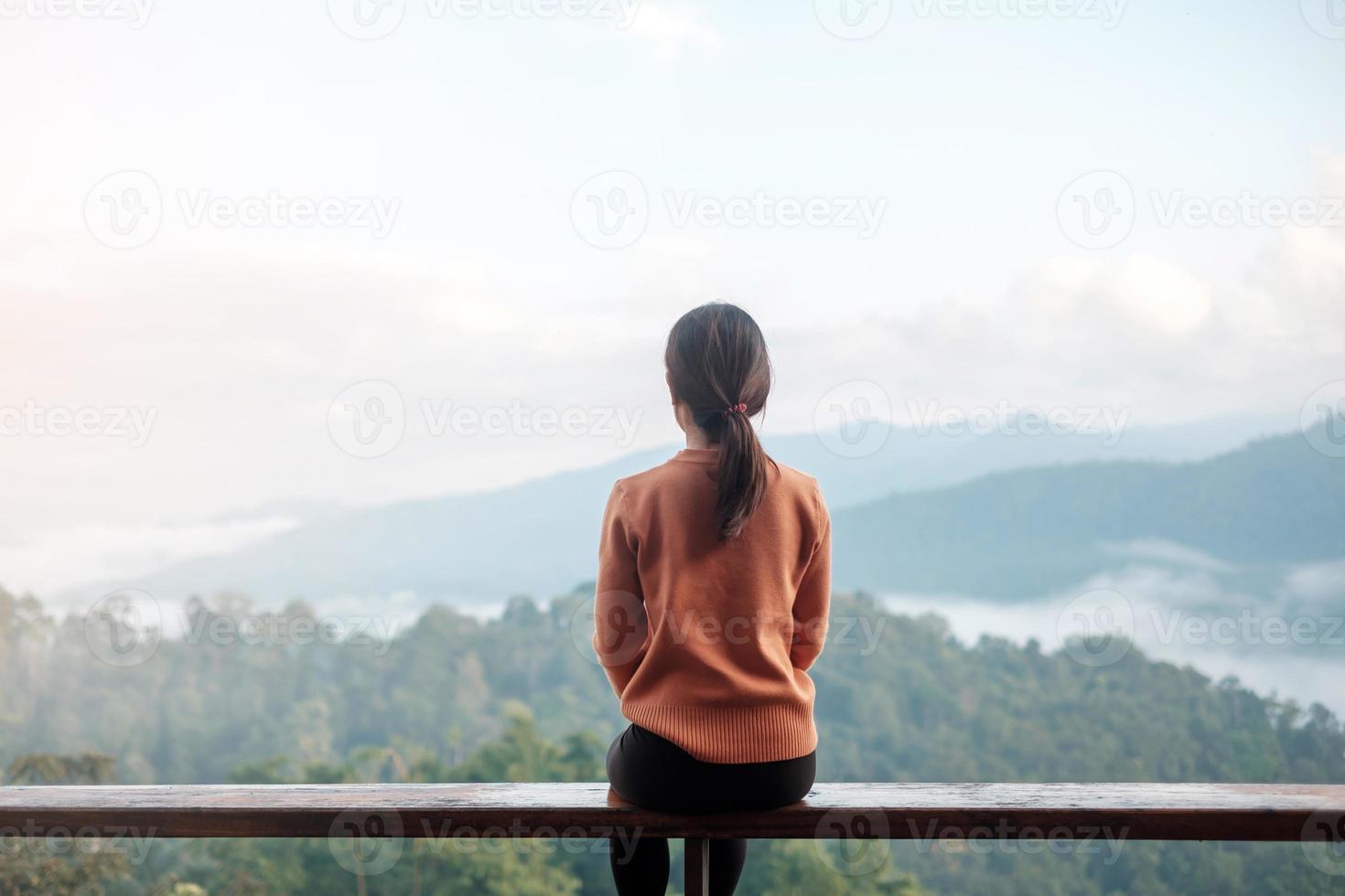 Happy woman relaxing and looking mountain view at countryside home or homestay in the morning. Vacation, blogger, SoloTravel, journey, trip and relaxing concept photo