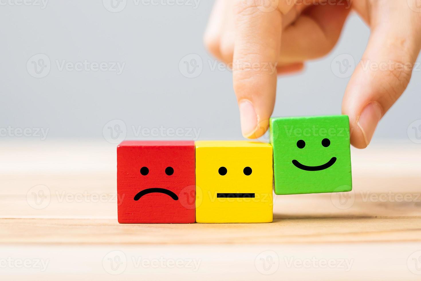 Hand holding Emotion face symbol wooden cube blocks. Service rating, ranking, customer review, satisfaction and feedback concept photo