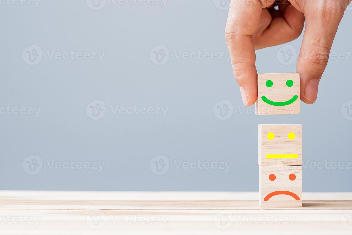 Hand holding smile face symbol on wooden cube blocks. Emotion, Service rating, ranking, customer review, satisfaction and feedback concept photo