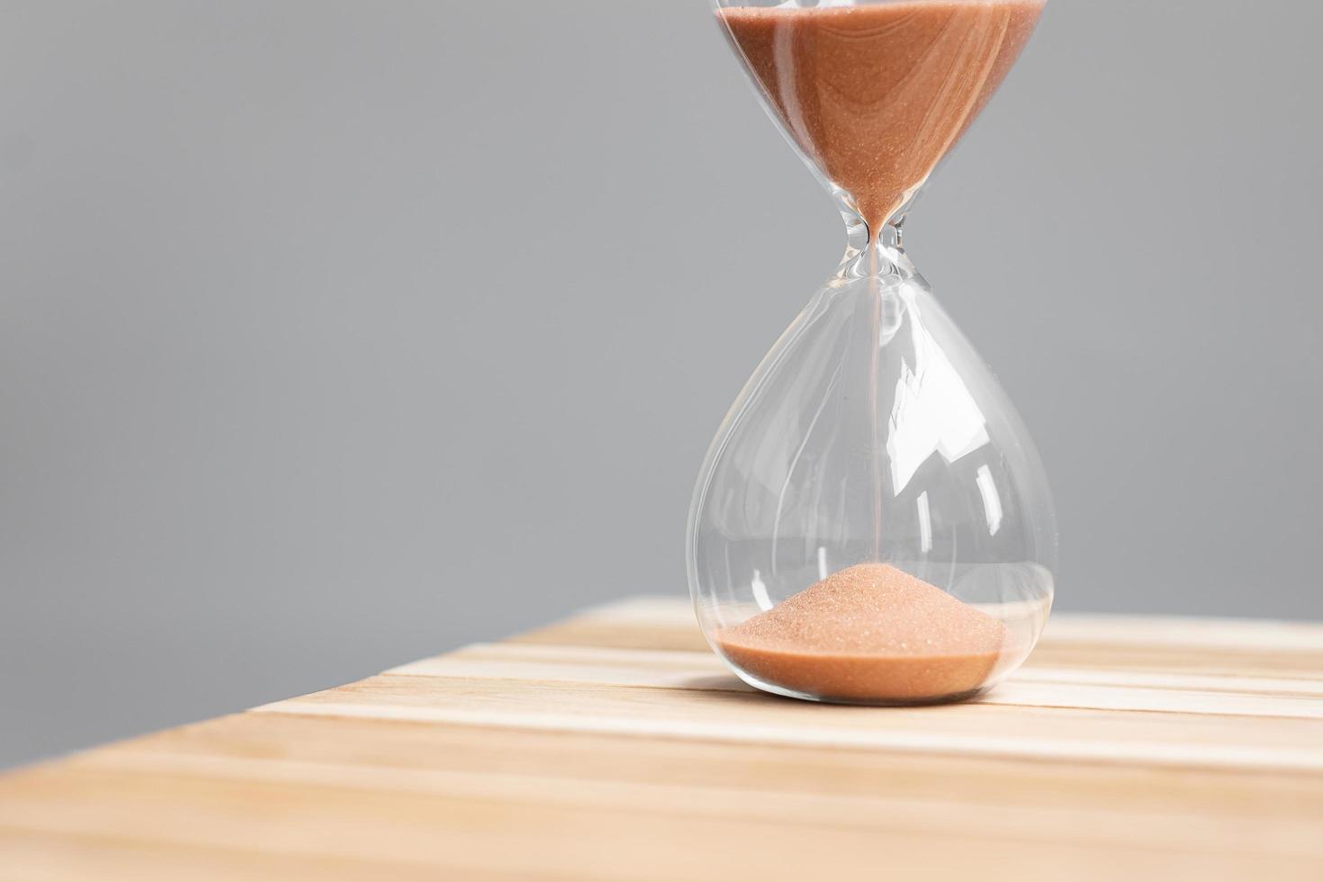 Hourglass on table office with copy space, Sand flowing through the bulb of Sandglass measuring the passing time. countdown, deadline, Life time and Retirement concept photo