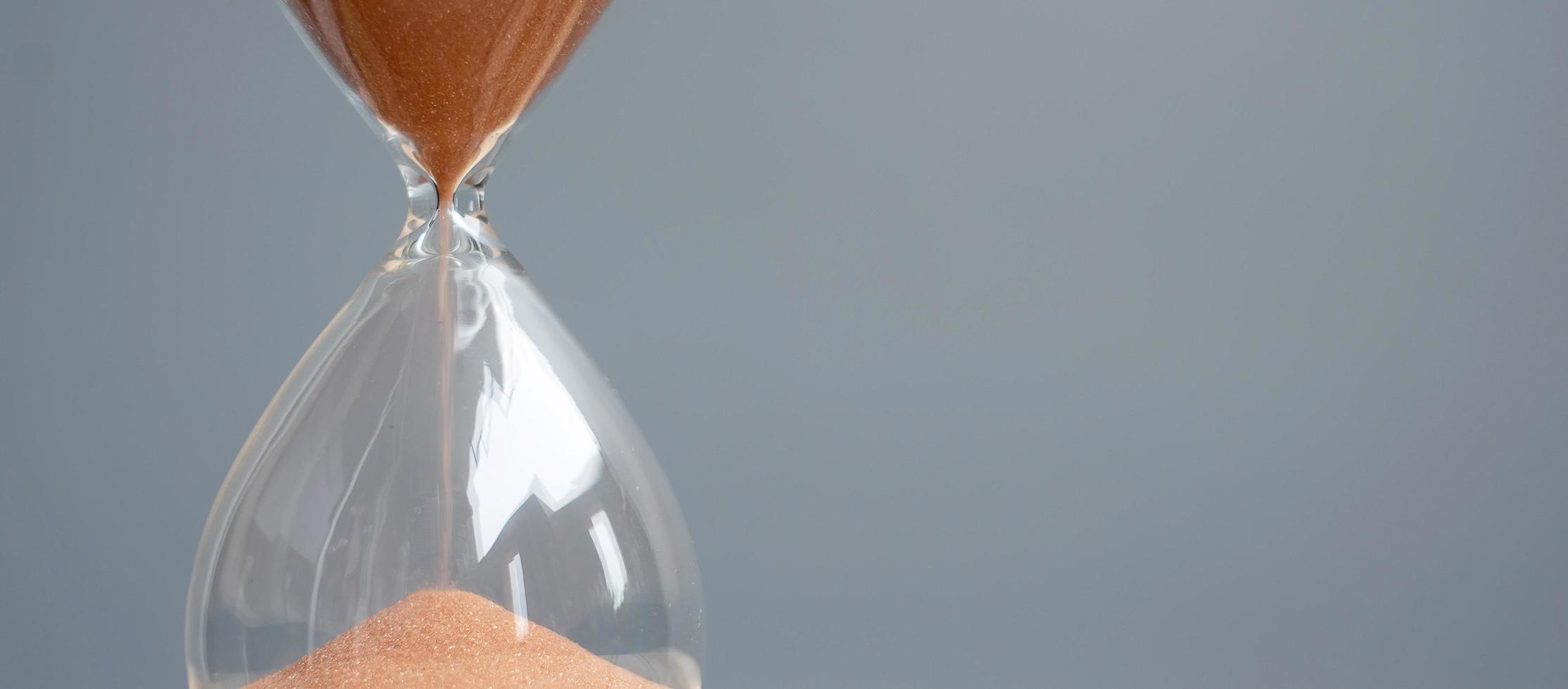 Hourglass on table office with copy space, Sand flowing through the bulb of Sandglass measuring the passing time. countdown, deadline, Life time and Retirement concept photo