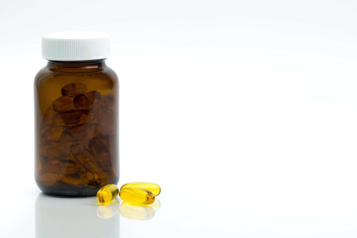 Yellow fish oil capsule pills with amber glass bottle with blank label on the table with copy space for text. Vitamins and supplements for heart care and joint care. Source of omega 3, EPA and DHA. photo