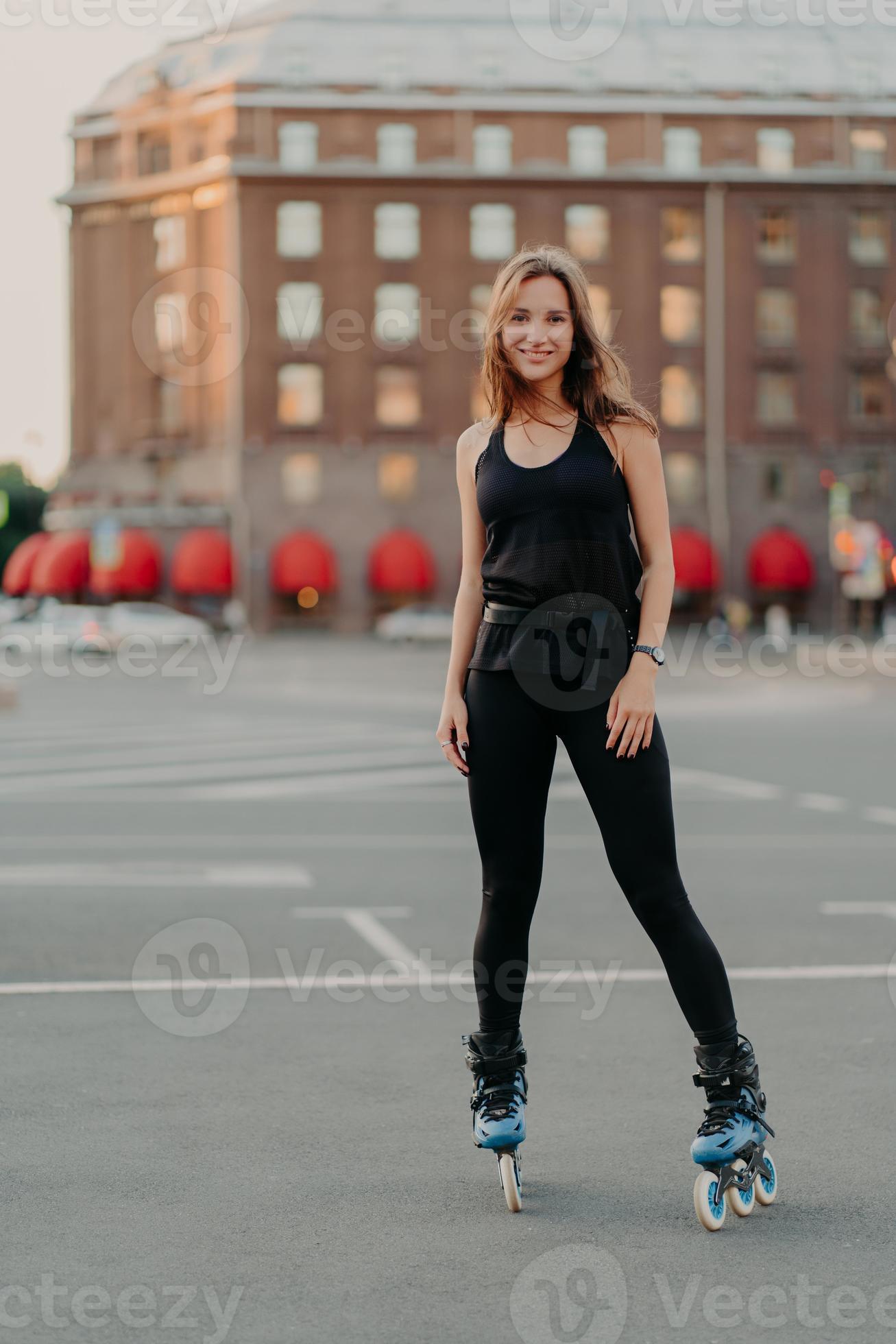 Vertical shot of healthy slim woman going rollerblading dressed in