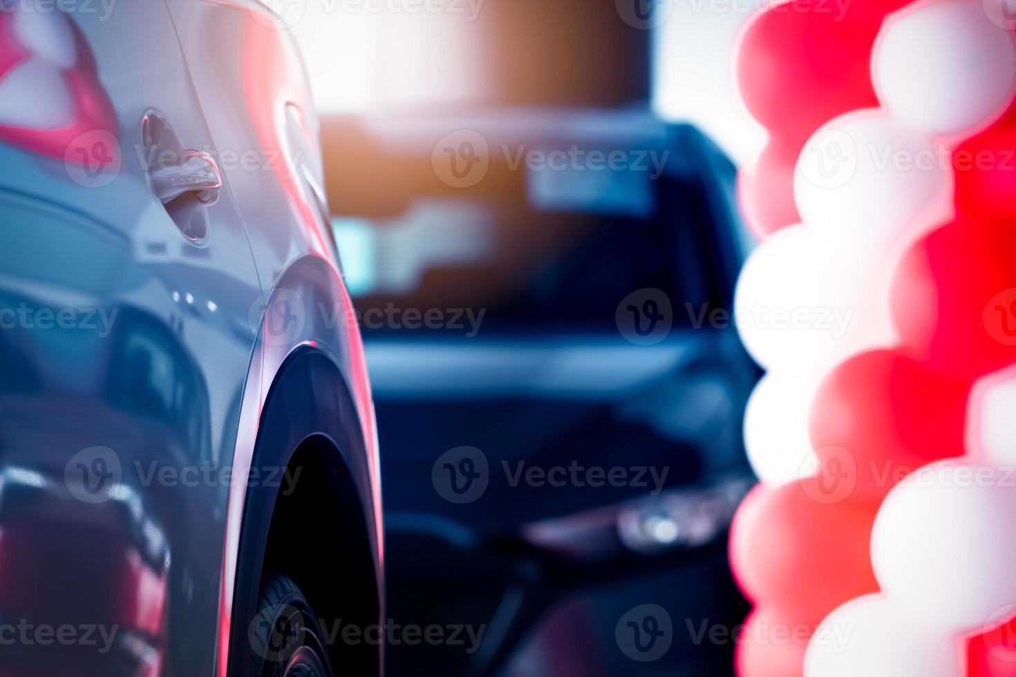 Selective focus SUV car parked in modern showroom. Car dealership concept. Automotive industry. Auto leasing business. Blurred showroom decor with red and white ballons for promotions and events. photo