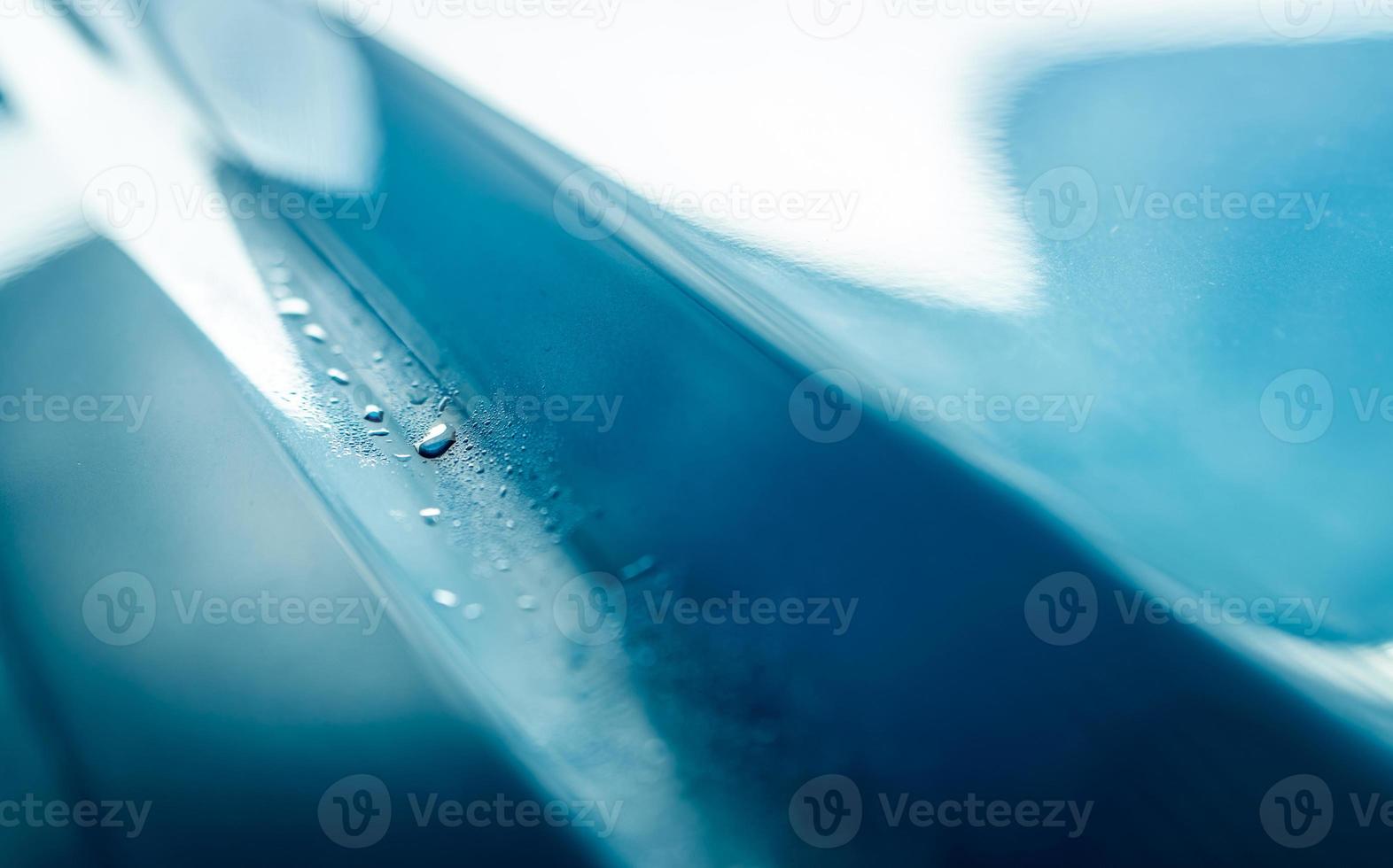 Closeup shiny blue car texture with water drops. Blue car is washing with water. Auto care business. Car with drops of water after cleaning with high pressure water spray. Car cleaning before waxing. photo