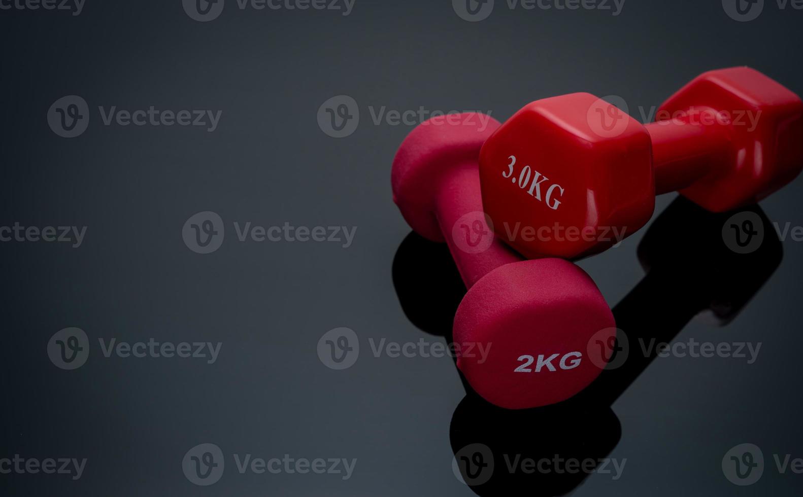 mancuernas rojas y rosas oscuras aisladas sobre fondo negro. Mancuernas de 2,3 kg. equipo de entrenamiento con pesas. accesorios de entrenamiento de musculación. equipo para hacer ejercicio en el gimnasio o en casa. equipo deportivo. foto