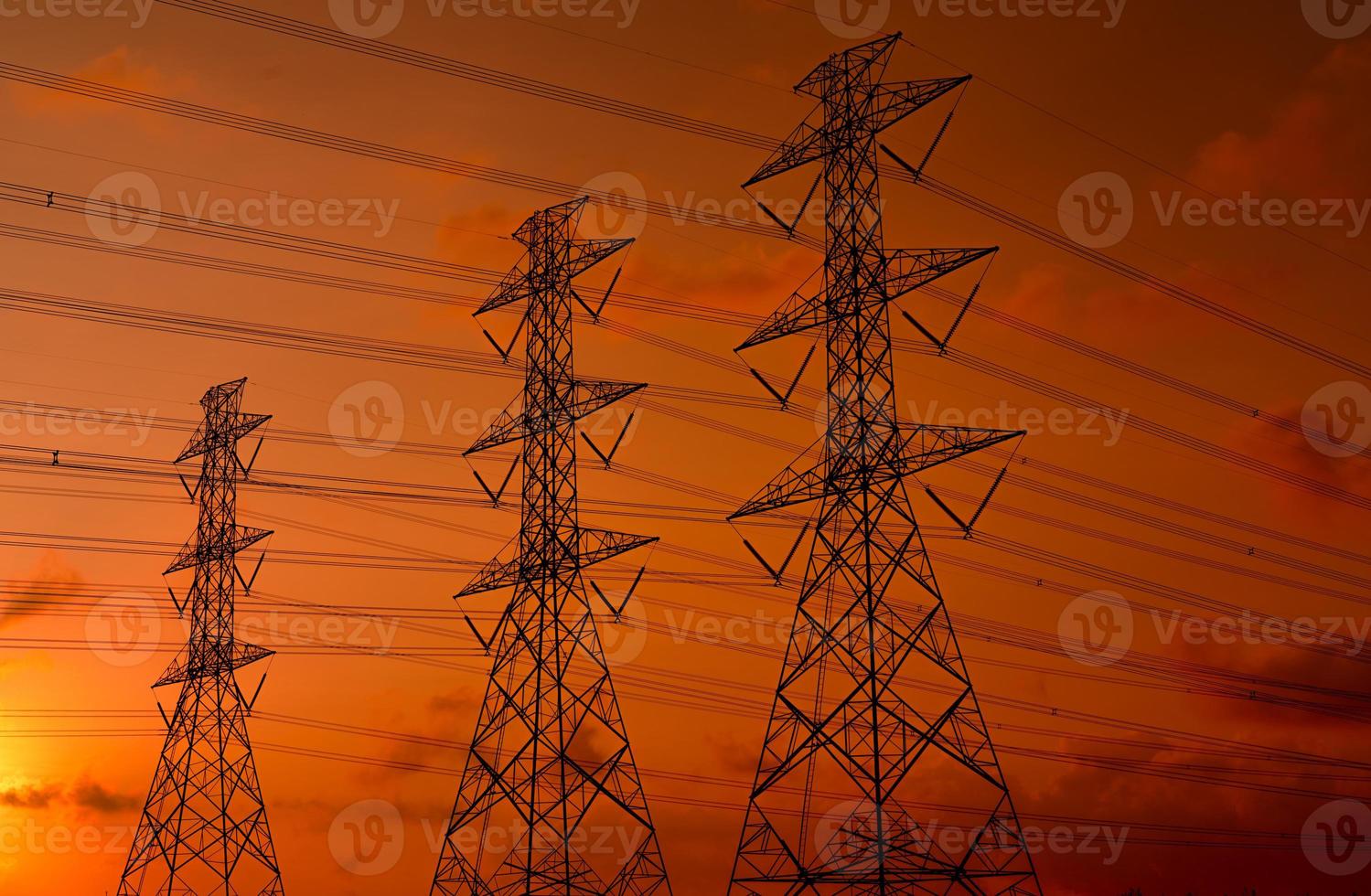 pilón eléctrico de alto voltaje y cable eléctrico con cielo al atardecer. postes de electricidad concepto de potencia y energía. torre de red de alto voltaje con cable de alambre. hermoso cielo de puesta de sol rojo-naranja. infraestructura. foto