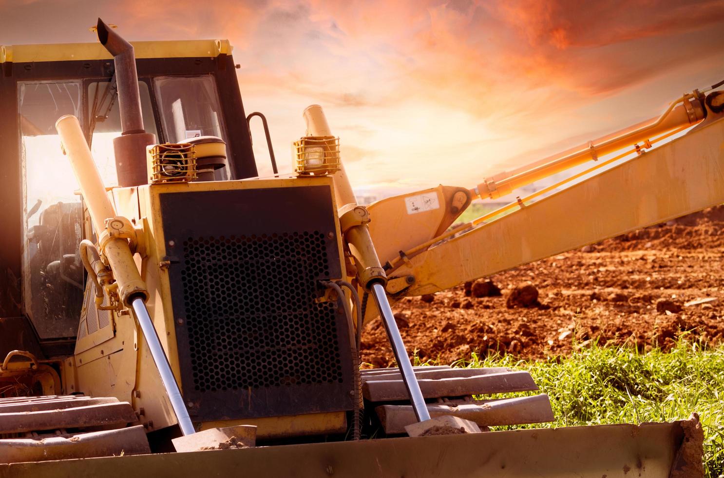 Selective focus on bulldozer on blur background of a backhoe at construction site. Excavation vehicle. Hydraulic arm. Land development business. Bulldozer for rent. Machine in construction industry. photo