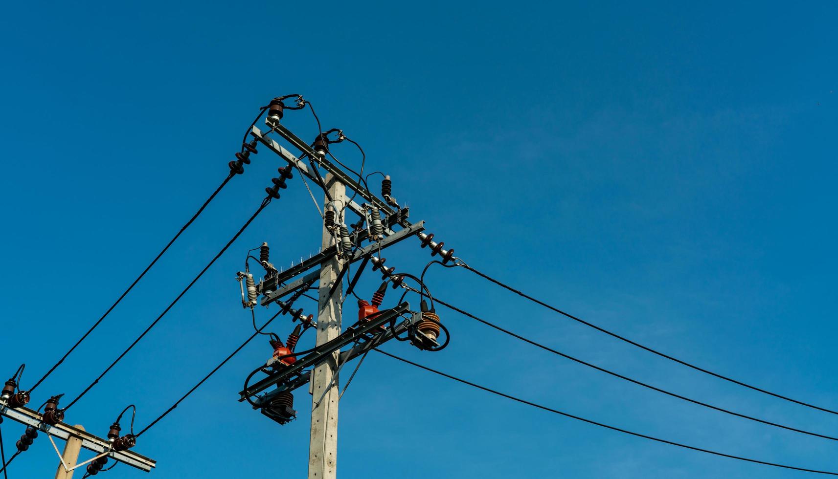 High voltage electric pole and transmission lines with clear blue sky. Electricity pylons. Power and energy engineering system. Danger high voltage tower. Cable wire on electric post. Power industry. photo