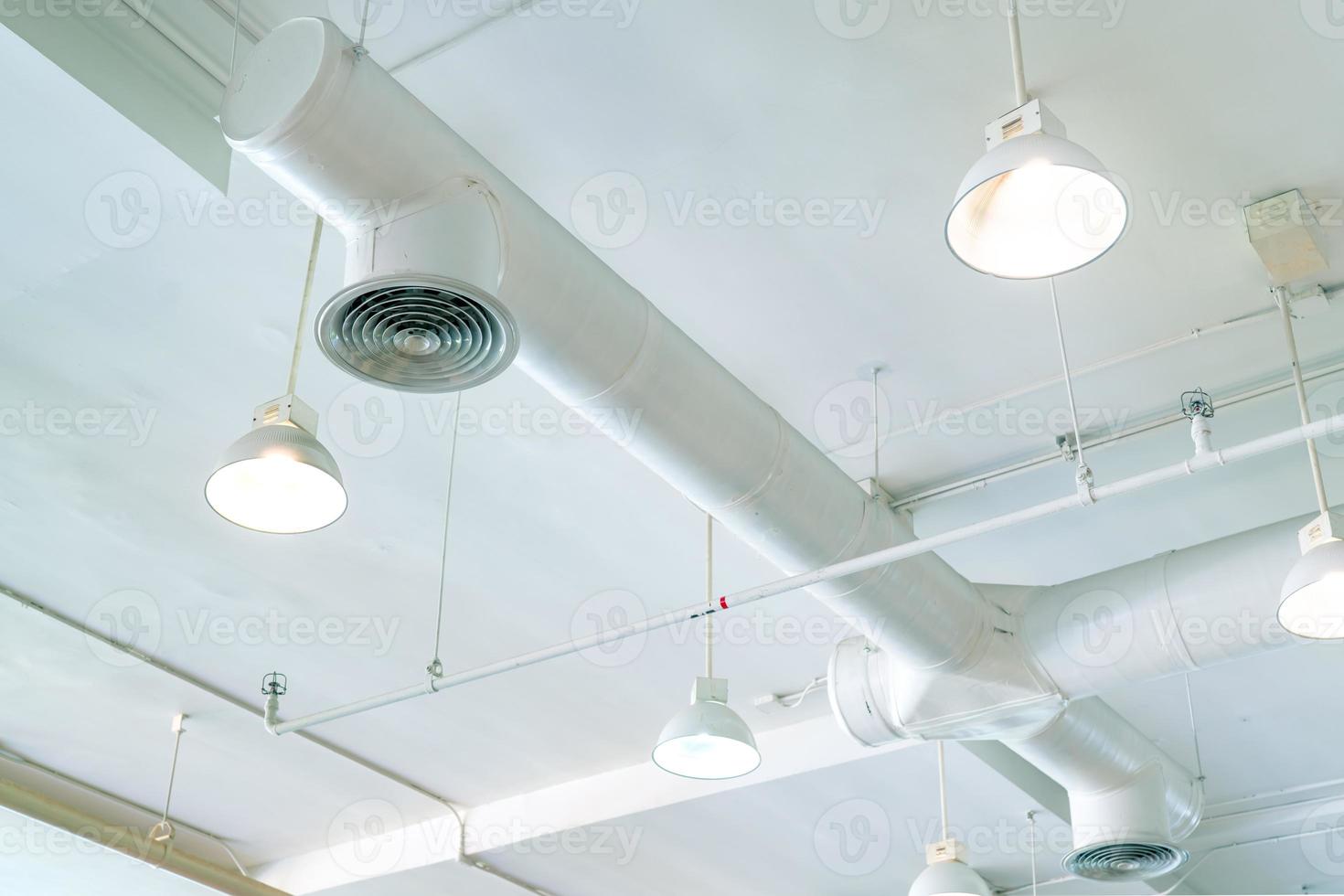 Air duct, air conditioner pipe and fire sprinkler system on white ceiling wall. Air flow and ventilation system. Building interior. Ceiling lamp light with opened light. Interior architecture concept. photo