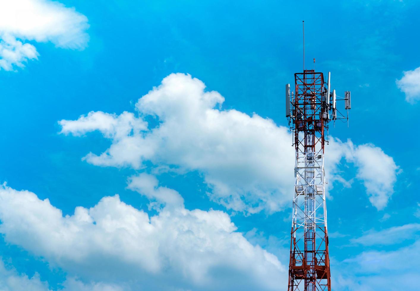 Telecommunication tower with blue sky and white clouds background. Antenna on blue sky. Radio and satellite pole. Communication technology. Telecommunication industry. Mobile or telecom 4g network. photo