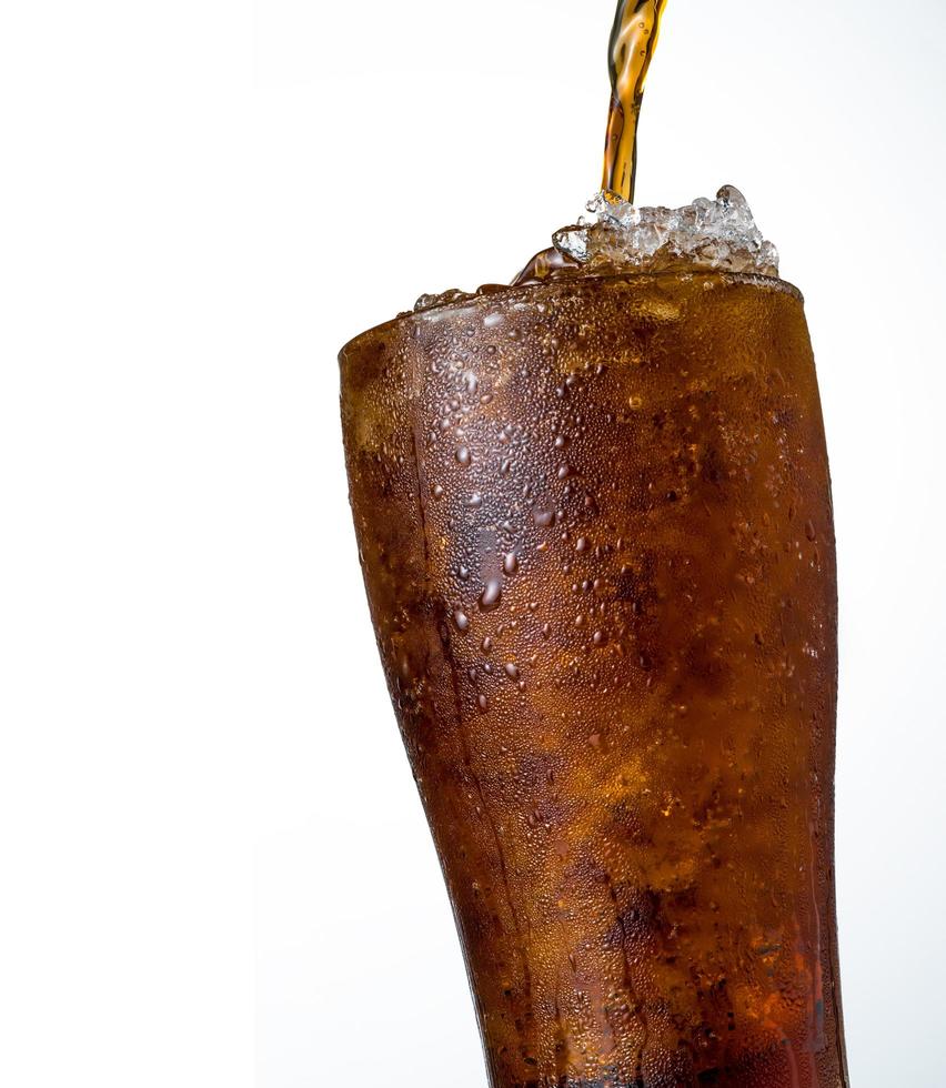 refresco con cubitos de hielo picado en vidrio aislado sobre fondo oscuro con espacio de copia. hay una gota de agua en la superficie de vidrio transparente. foto