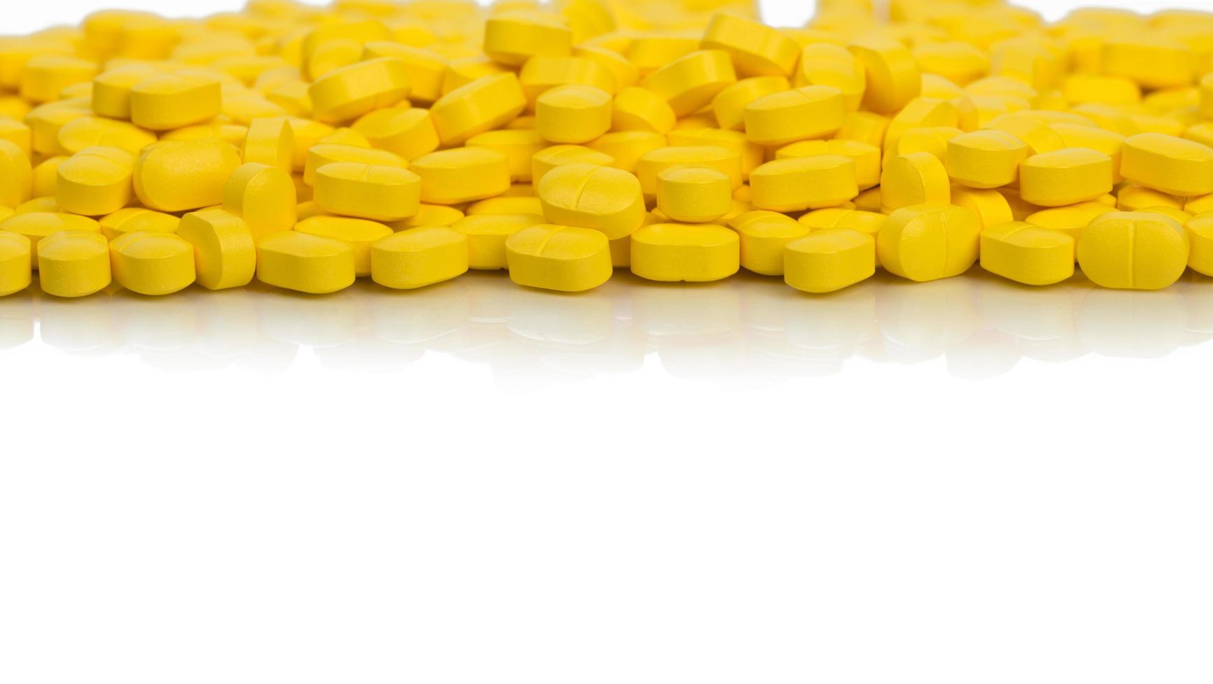 Pile of yellow ovoid-rectangular shape tablet pills isolated on white background with copy space. medicine for relief pain. Pharmaceutical industry. Global healthcare concept. photo