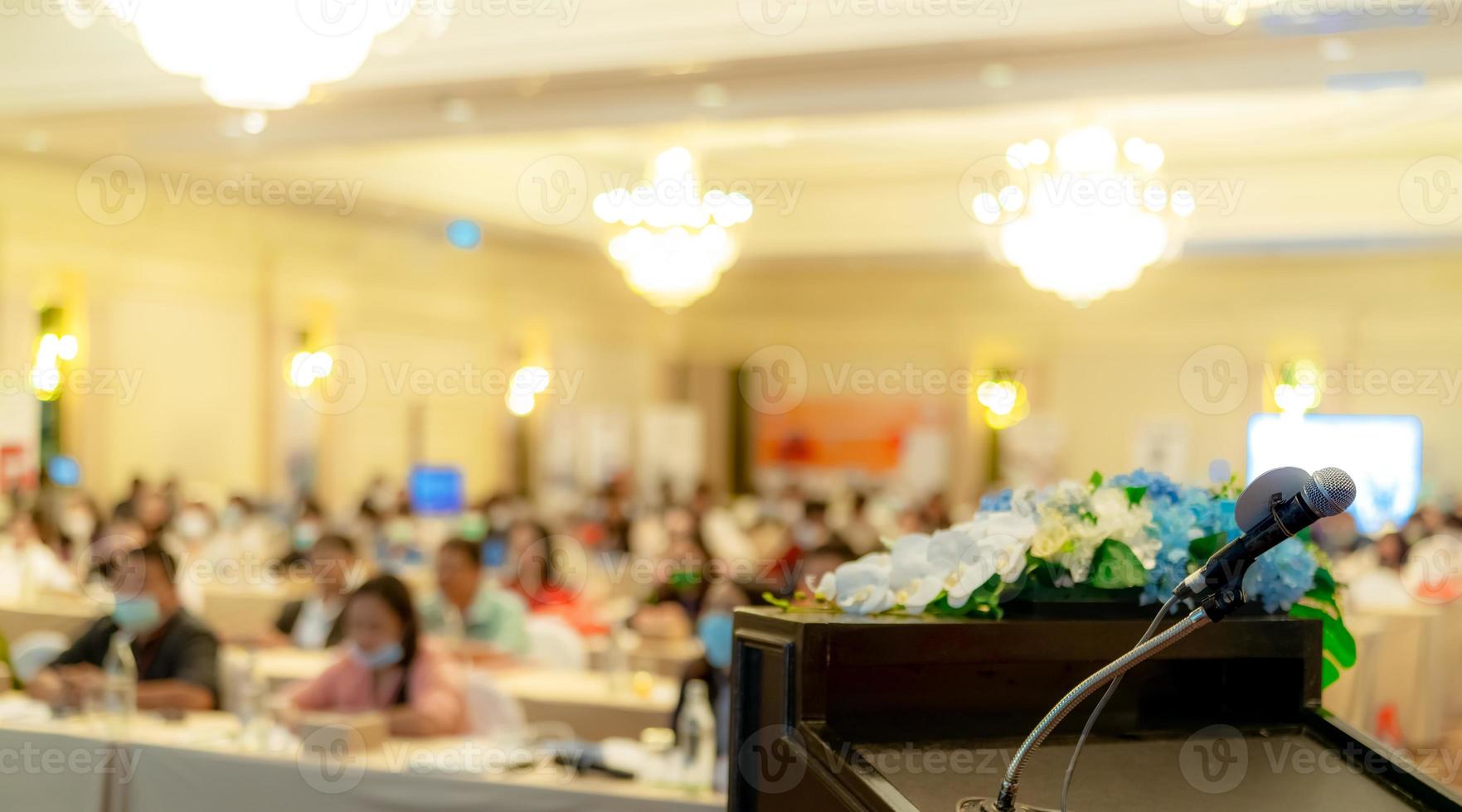 Microphone on stand at podium stage for public speaking or speech in conference hall. Mic for speaker on stage of event. Meeting and presentation in seminar room. Microphone for talking to audience. photo