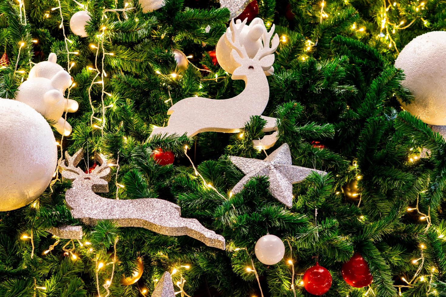 cierra la decoración del árbol de navidad con bolas rojas, doradas, plateadas y blancas, estrella plateada y reno blanco. fondo de navidad. fondo de navidad y feliz año nuevo. bola de colores en el árbol de navidad. foto