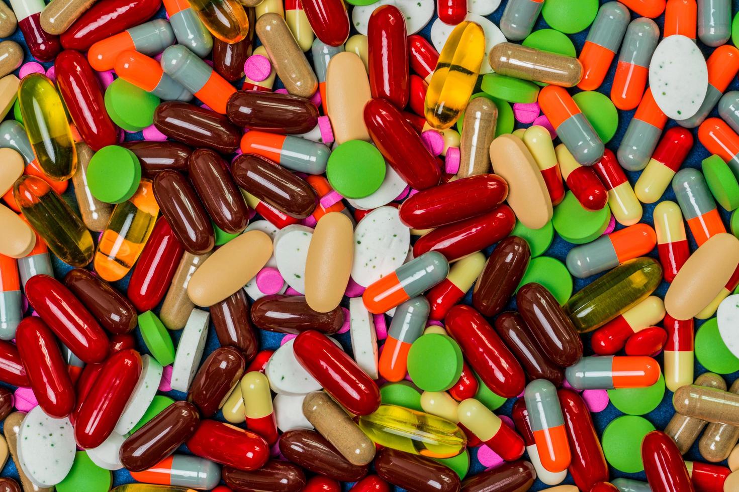 Pile of colorful tablets and capsule pills. Full frame of medicine, vitamins and supplements. Top view many of pills background. Drug, vitamin, supplement and herbal medicine interaction concept. photo