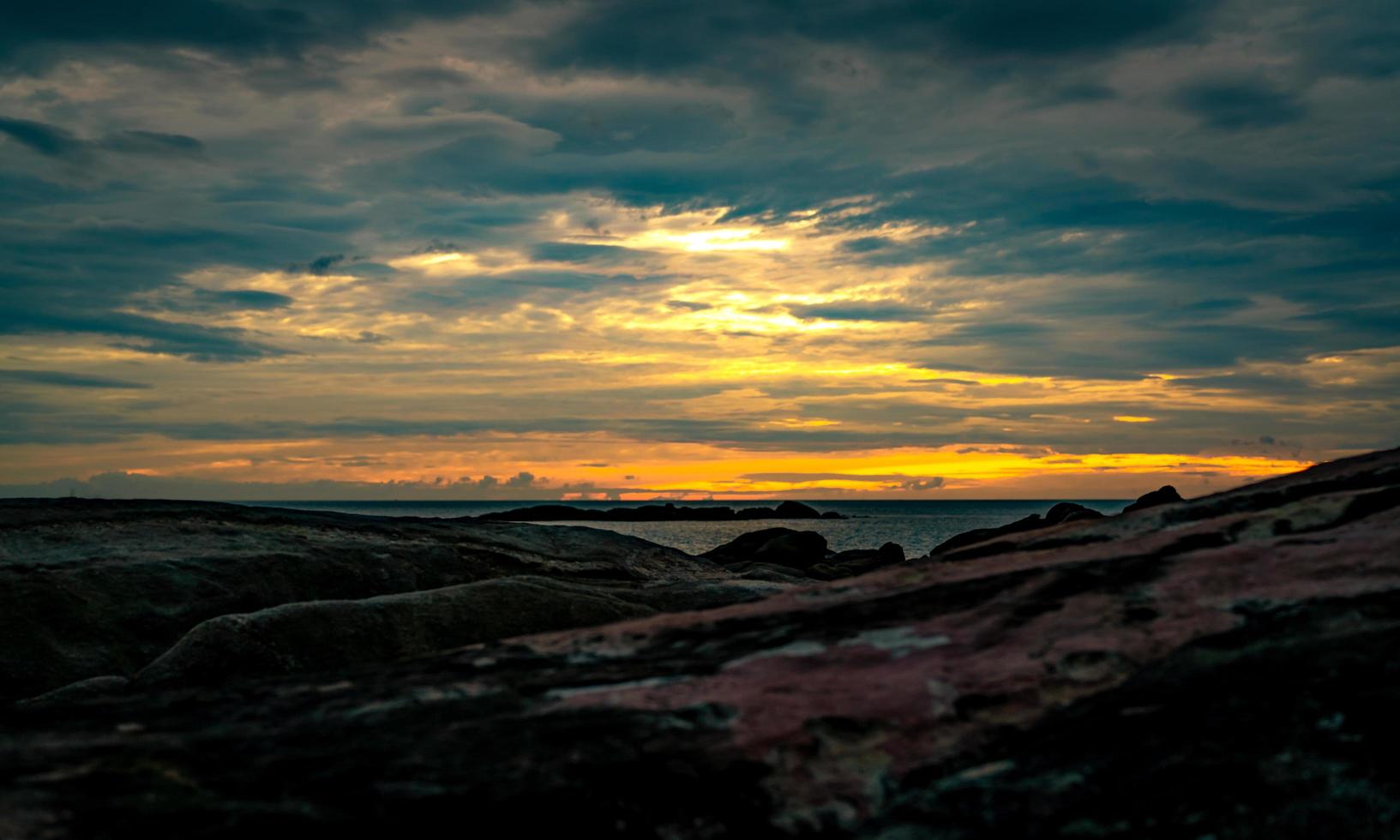 Beautiful stone beach in the morning with golden sunrise sky. Peaceful and tranquil scene. Landscape of calm sea in the morning. Seascape with skyline. Tropical sea. Beauty in nature. Rock beach. photo