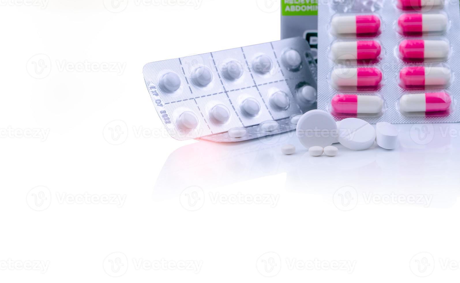 White tablets pills on white table and blurred pink-white capsule pills in blister pack. Pharmaceutical products. Pharmaceutical industry. Round and oval tablets pills. Healthcare and pharmacy. photo
