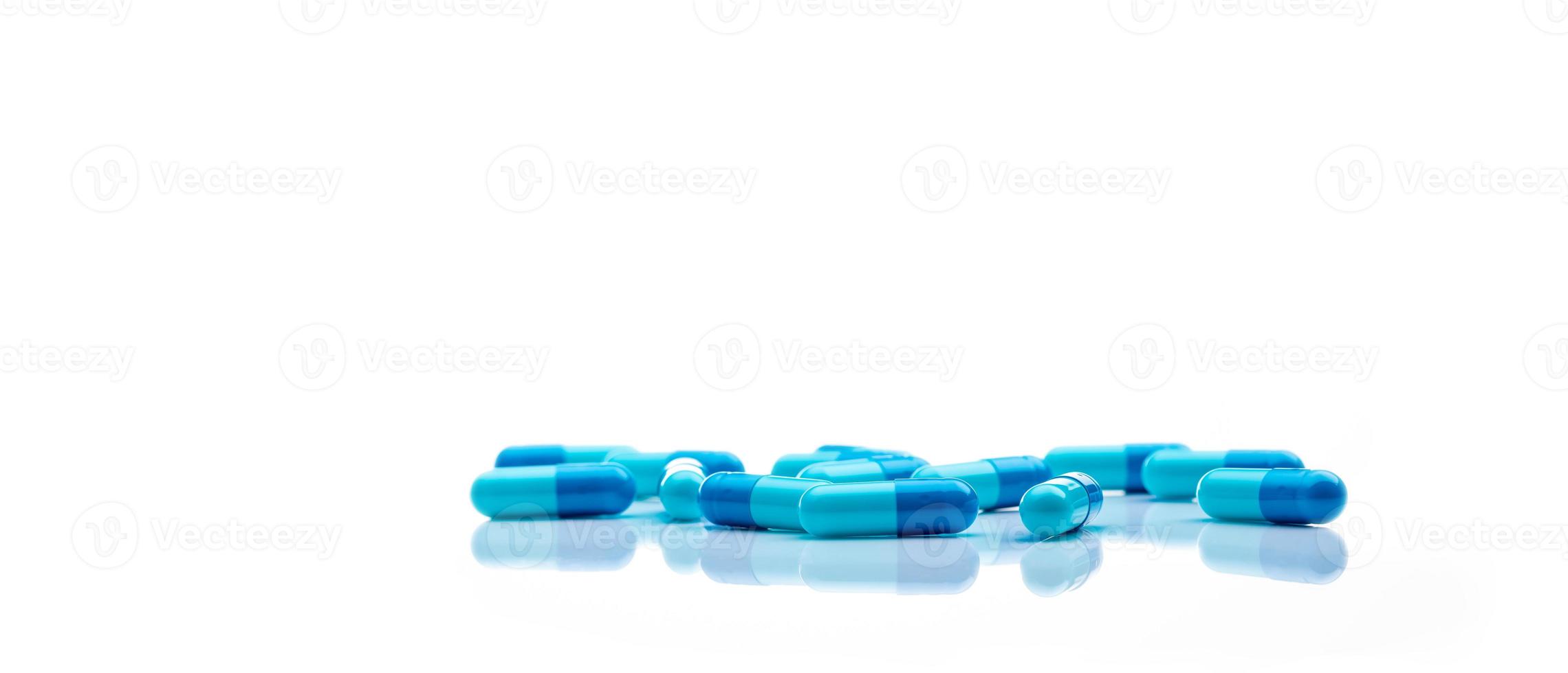 Blue antibiotic capsule pills spread on white background. Antibiotic drug resistance. Pharmaceutical industry. Healthcare and medicine concept. Health budget concept. Capsule manufacturing industry. photo