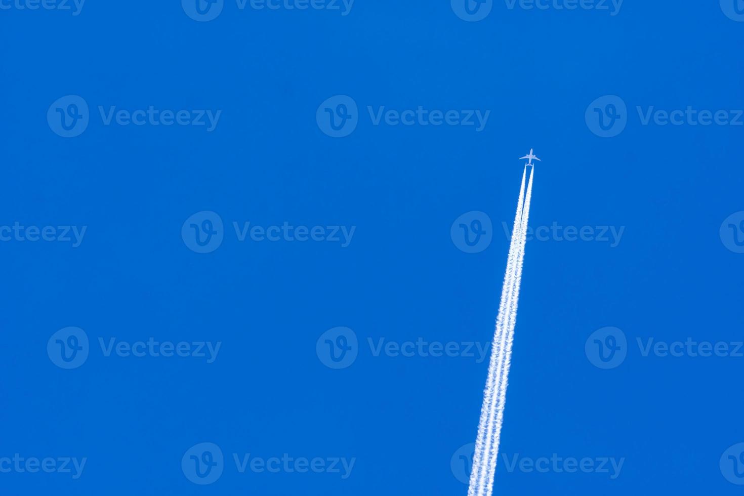 Airplane with white condensation tracks. Jet plane on blue sky and white clouds with vapor trail. Travel by airplane concept. Trails of exhaust gas from airplane engine. Aircraft with white stripes. photo