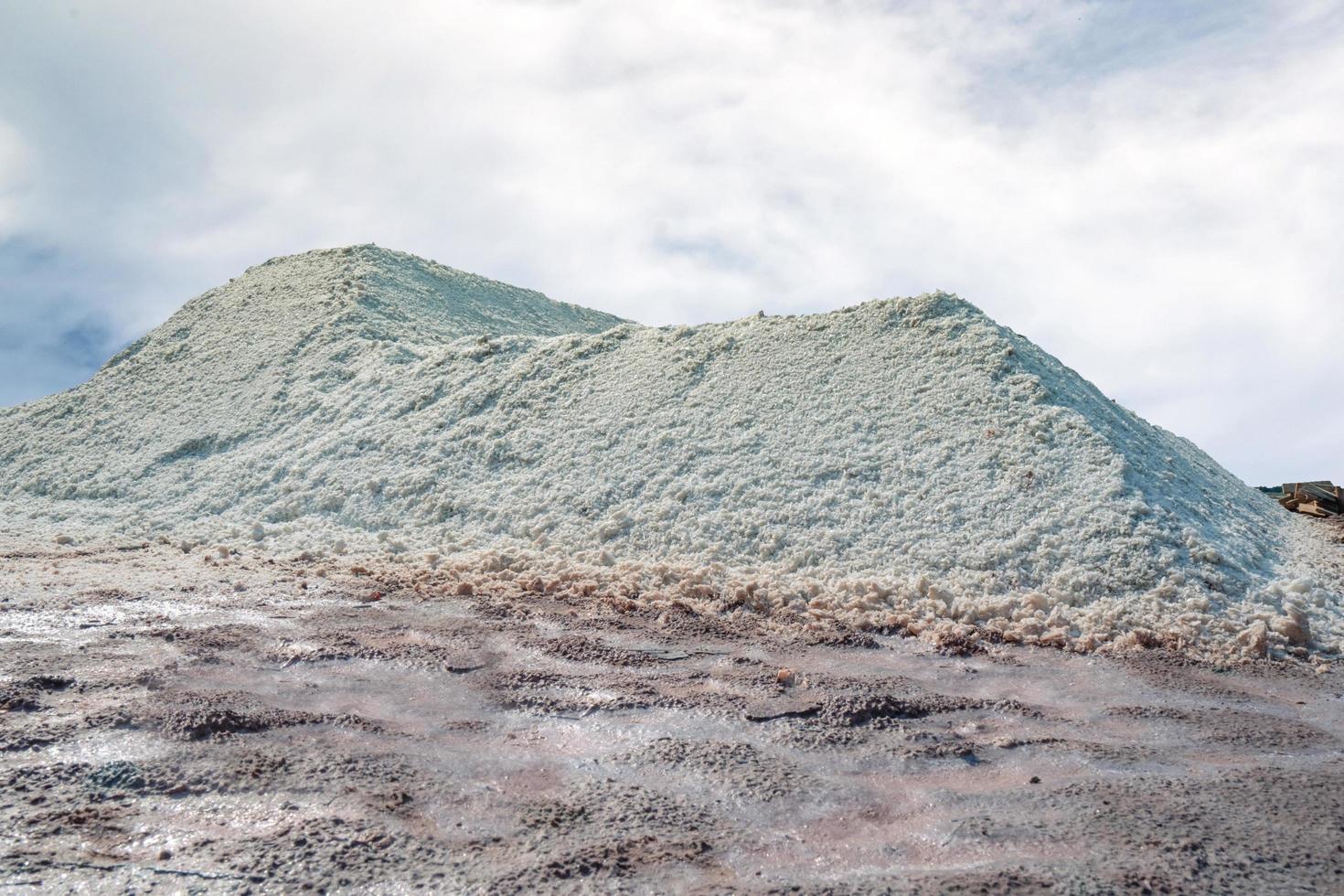 Granja de salmuera con cielo y nubes. montón de sal marina orgánica. materia prima de sal industrial. sal del océano mineral de cloruro de sodio. evaporación y cristalización del agua de mar. fuente de yodo foto