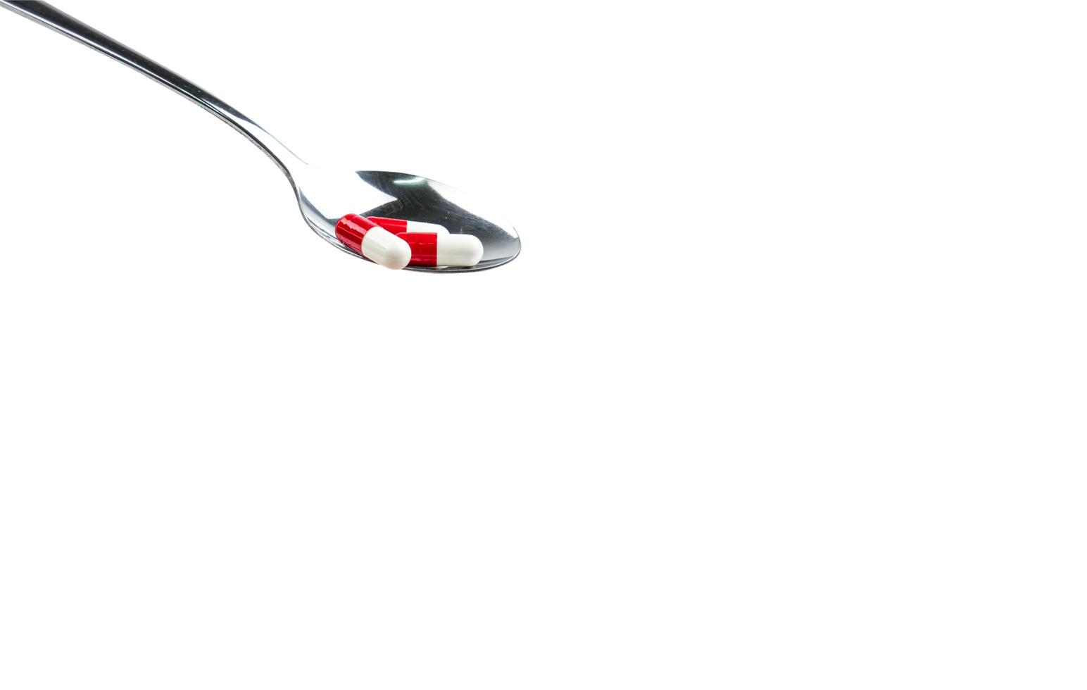Antibiotic capsule pills in stainless steel spoon isolated on background with copy space and clipping path. Drug resistance concept. Antibiotics drug use with reasonable and global healthcare concept. photo