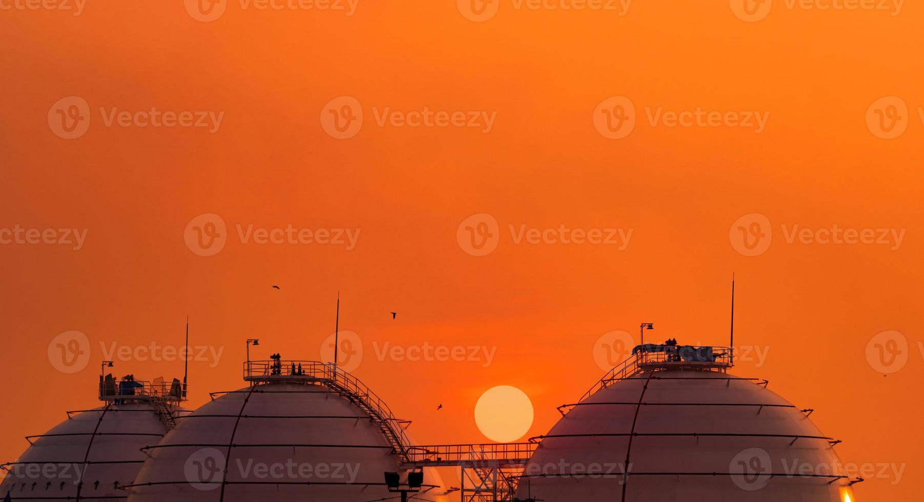 Industrial gas storage tank on orange sunset sky. LNG or liquefied natural gas storage tank. Spherical gas tank in petroleum refinery. Above-ground storage tank. Natural gas storage industry. photo