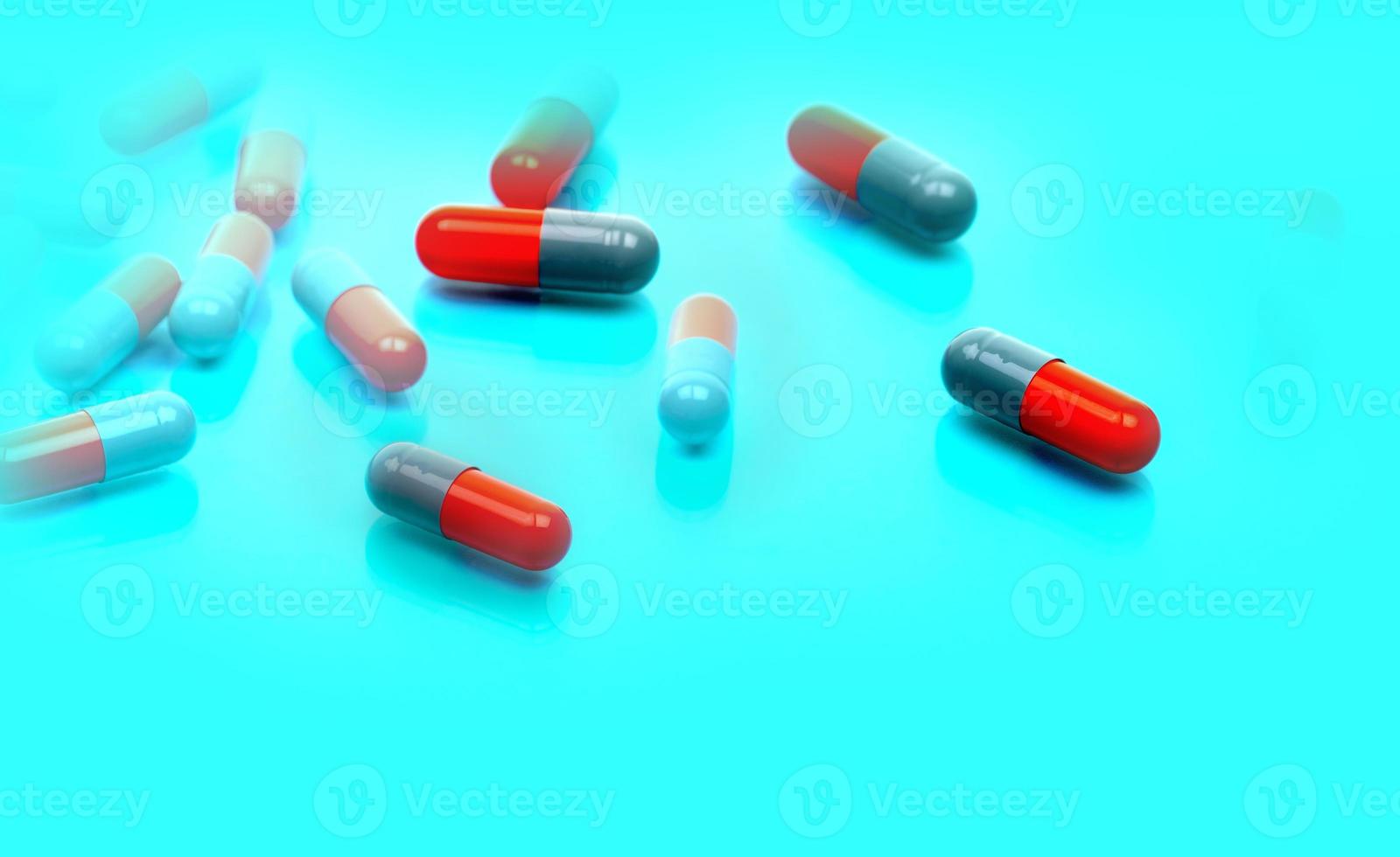 Selective focus on gray-orange antibiotic capsule pills on blue background. Pharmaceutical industry. Toxicology and pharmacology concept. Antibiotic drug resistance. Capsule pills manufacturing. photo