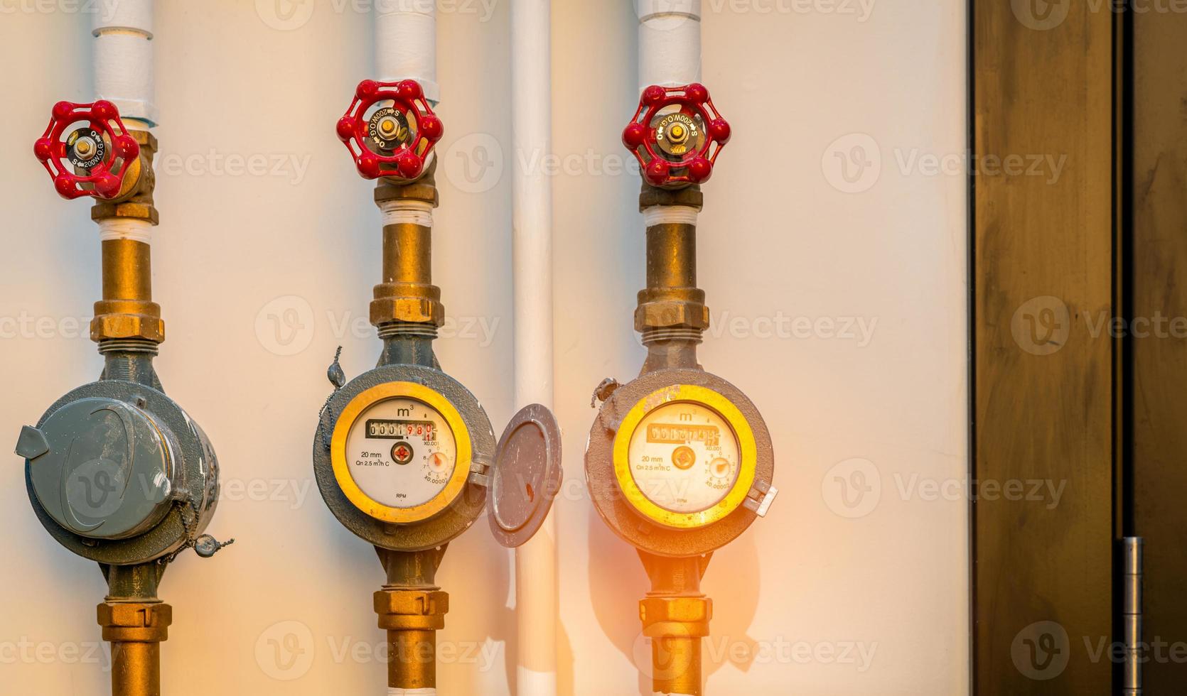 medidor de agua único y válvulas en la pared de hormigón blanco de la casa. consumo de agua y concepto de factura. medidores de agua instalados en la tubería de latón del edificio. contadores de agua residenciales. lectura de medidor de agua. foto