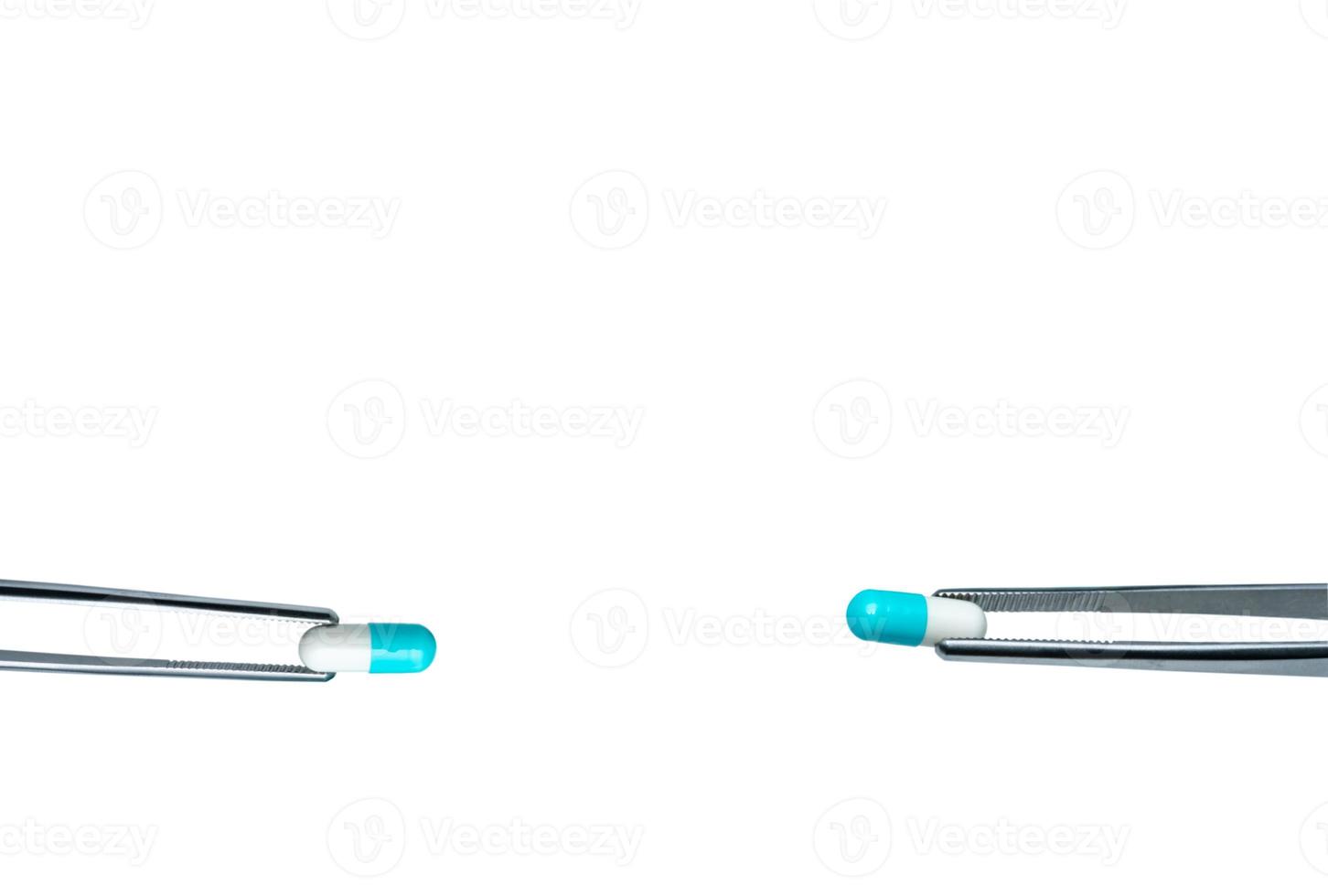 Two forceps pick white-blue capsule pills. Drugs choose for test in lab. Antibiotic drug selection. Antibiotic drug resistance concept. QA and QC in pharmaceutical factory concept. Drugs of choice. photo