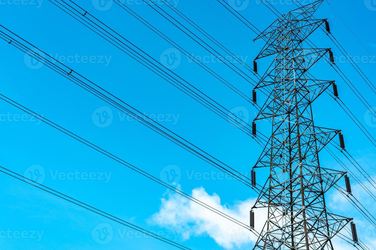 High voltage electric tower and transmission lines. Electricity pylons with blue sky and white clouds. Power and energy conservation. High voltage grid tower with wire cable at distribution station. photo