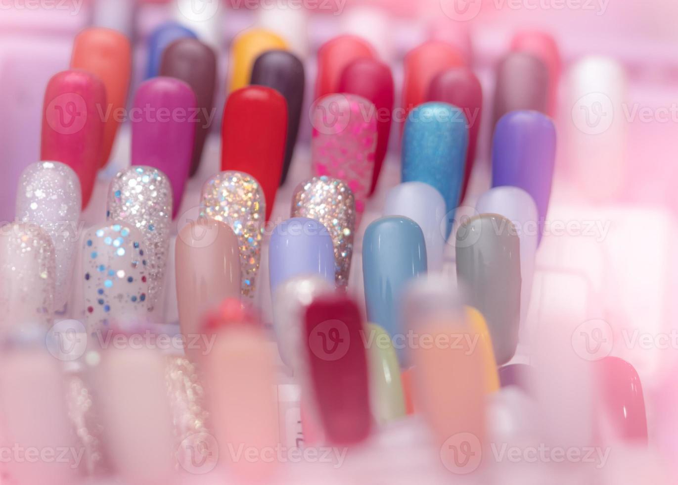 uñas artificiales coloridas en la tienda de salón de uñas. juego de uñas postizas para que el cliente elija el color para la manicura o la pedicura en el salón de uñas y en la tienda de spa. arte y diseño de uñas. Muestra de paleta de esmalte de uñas. foto