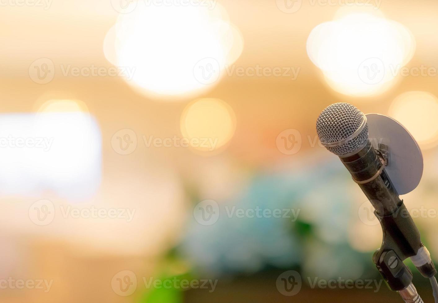 Microphone on stand at podium stage for public speaking or speech in conference hall. Mic for speaker on stage of event. Meeting and presentation in seminar room. Microphone for talking to audience. photo